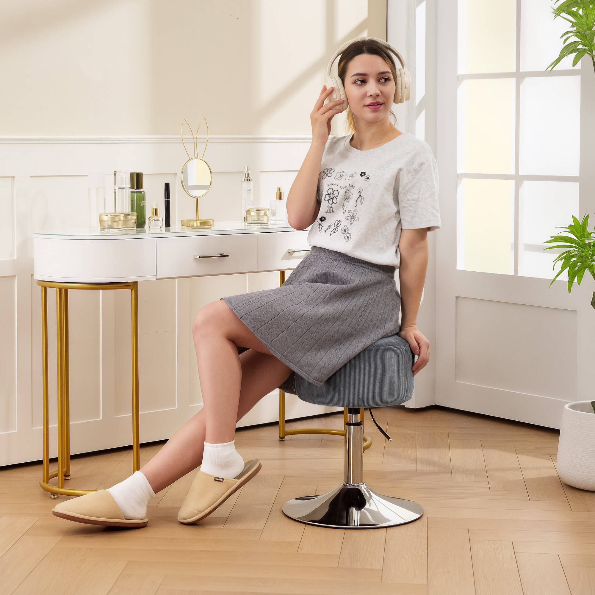 Una mujer con auriculares se sienta en un taburete frente a un tocador con cosméticos.