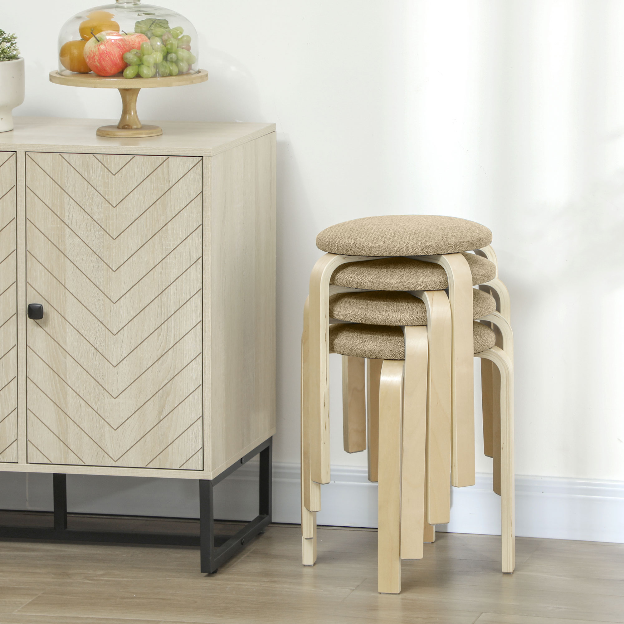 Un mueble de madera clara con patrón de cheurón y cuatro taburetes de madera apilados.
