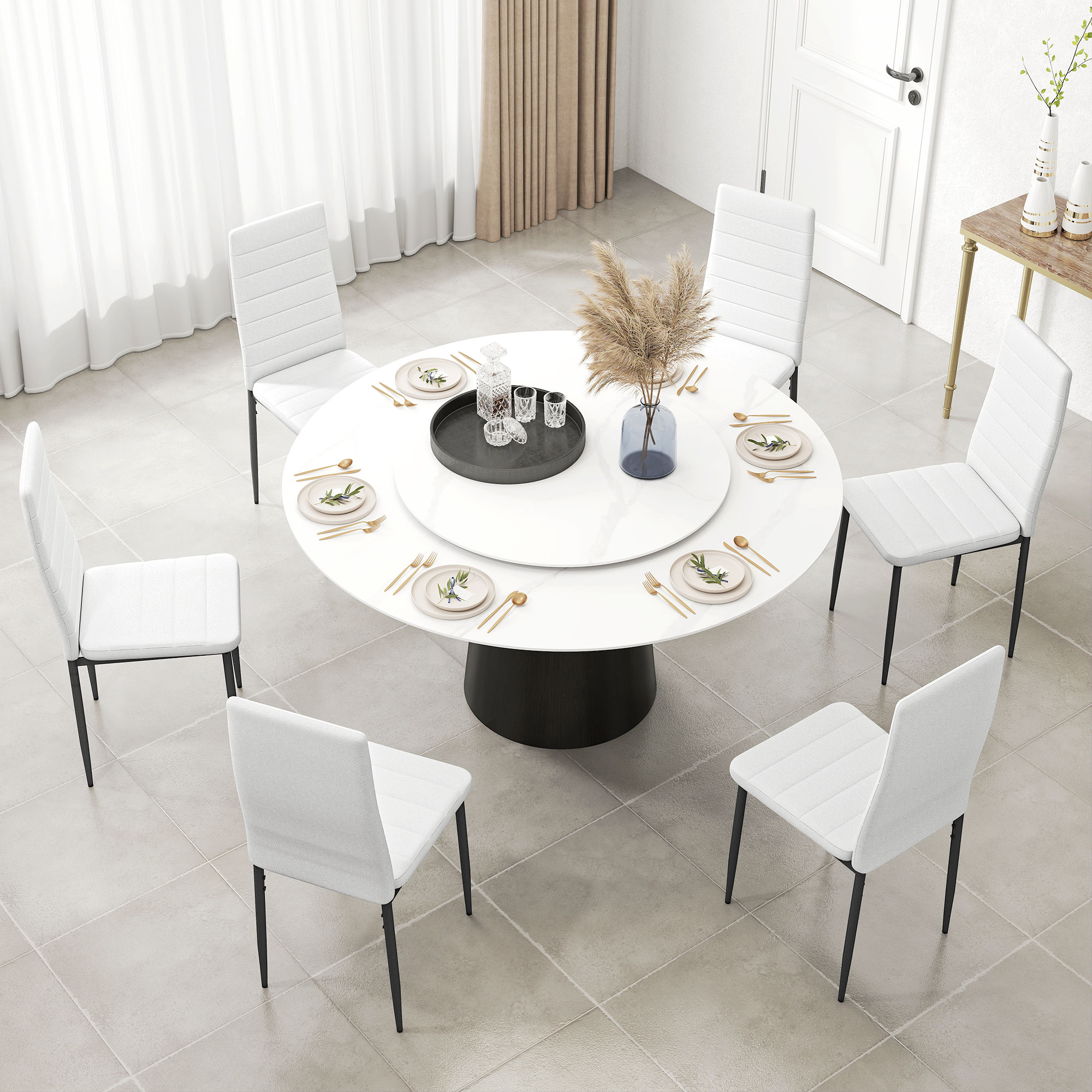 Una mesa de comedor redonda con sillas blancas, decorada con cubiertos dorados y un arreglo floral.