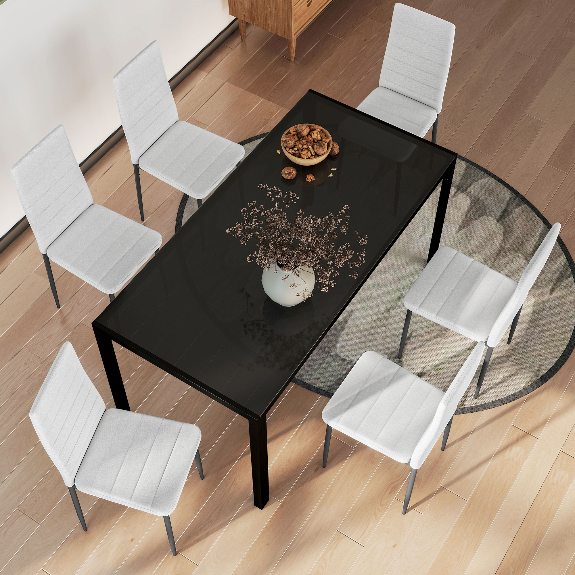 Un comedor moderno con mesa de cristal negro, seis sillas blancas y un jarrón con flores.
