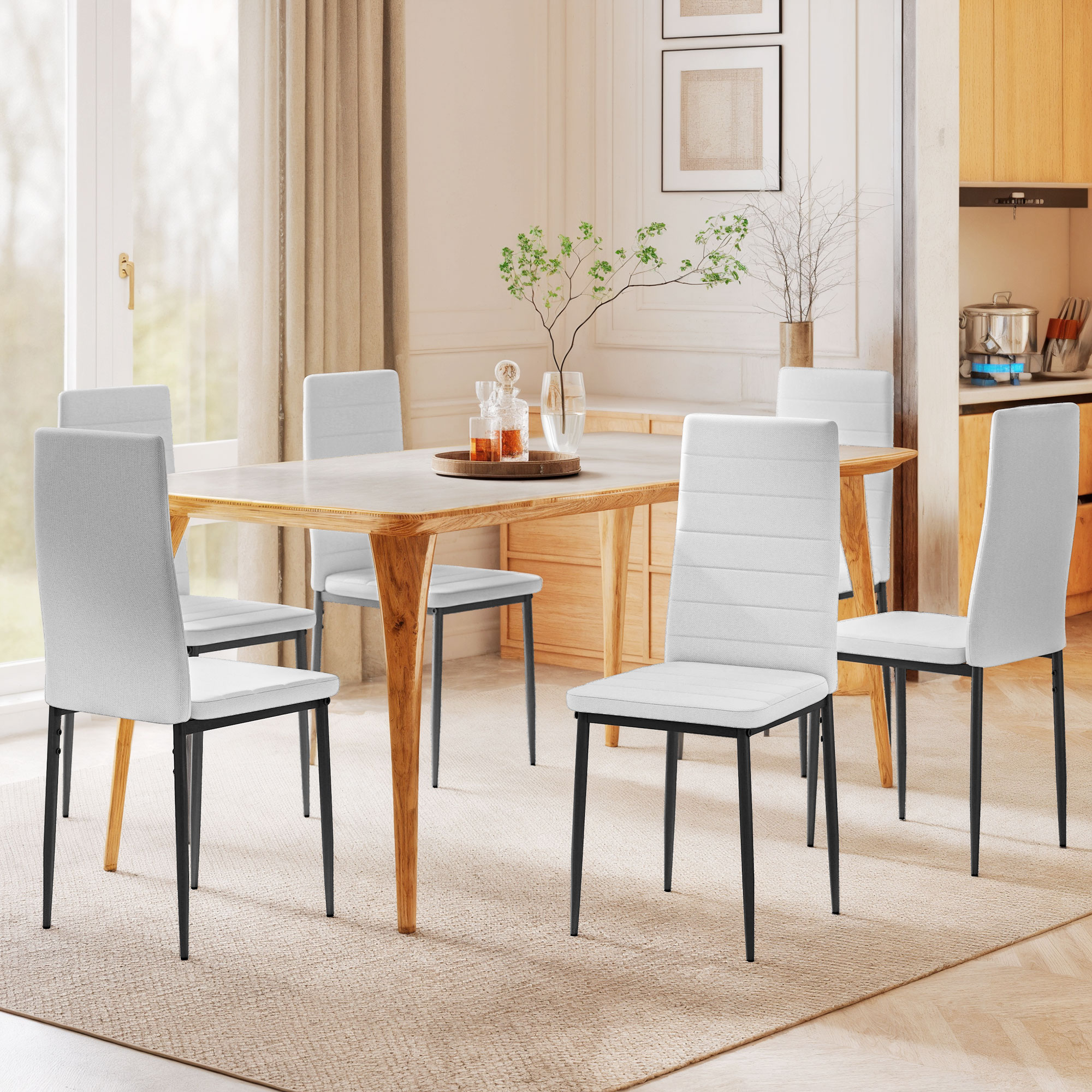 Una mesa de comedor con seis sillas blancas en una habitación luminosa con cortinas y elementos de madera.