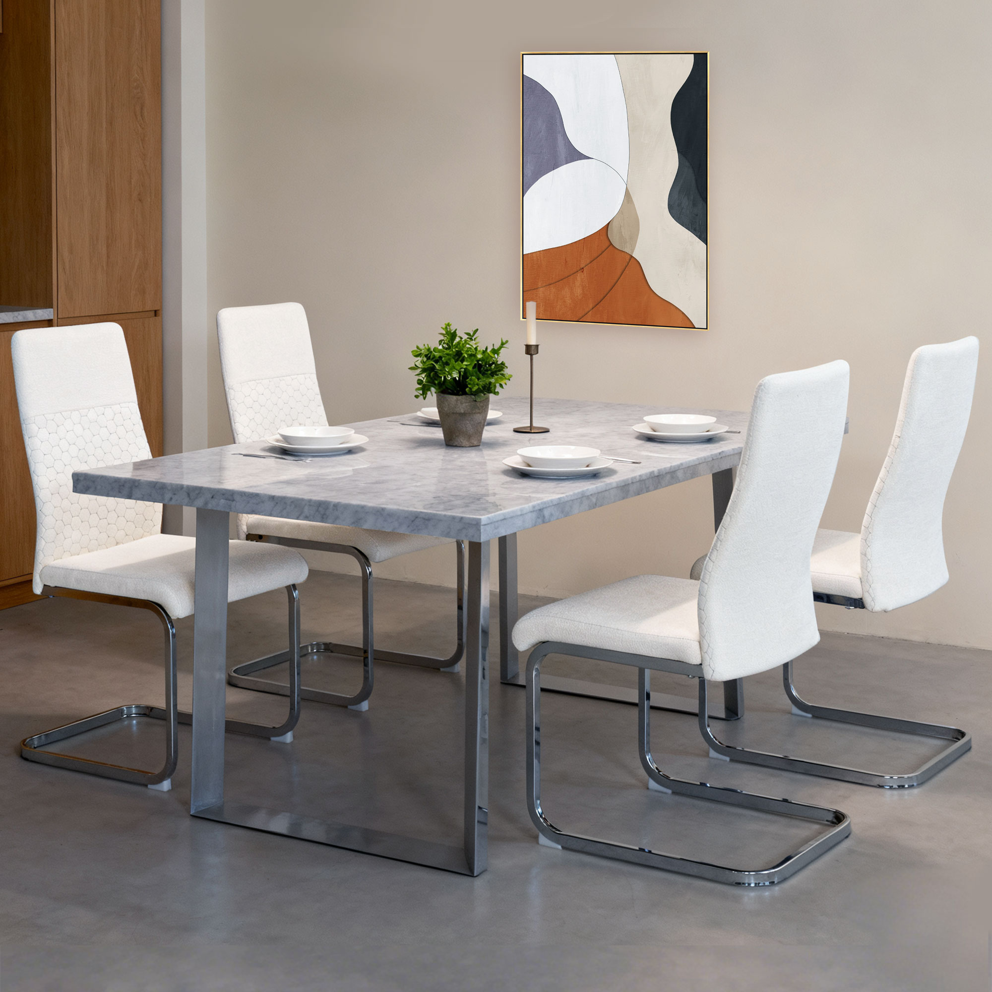 Una mesa de comedor de mármol con cuatro sillas blancas, un armario y arte de pared.