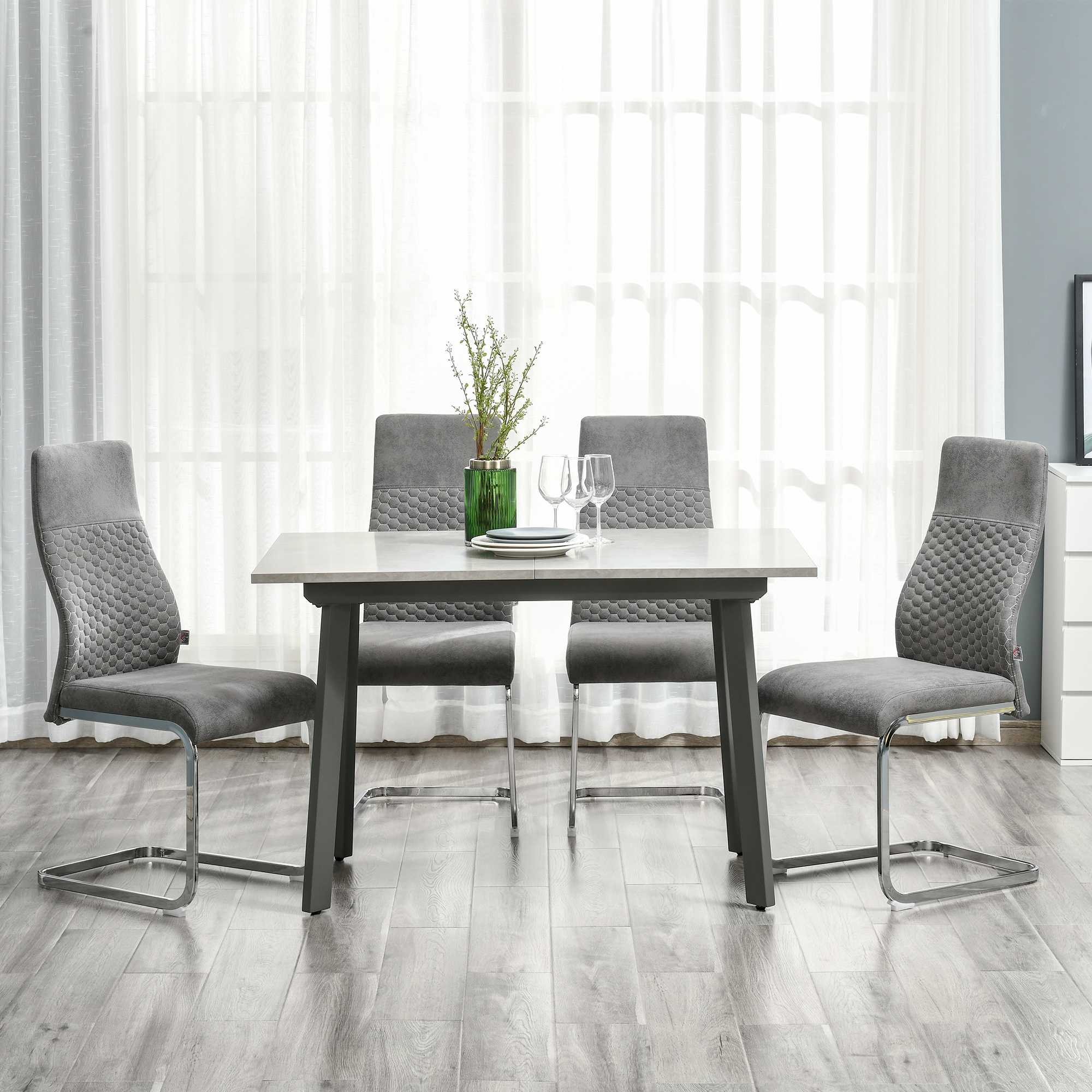 Comedor gris con mesa, cuatro sillas, jarrón y vajilla.