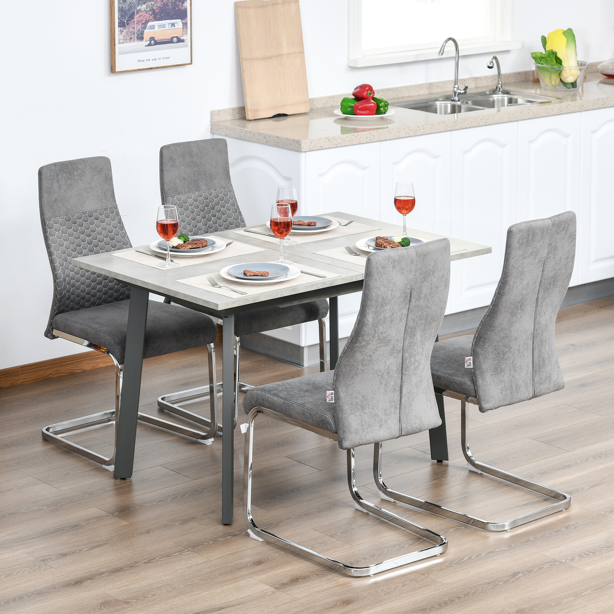 Una mesa de comedor con cuatro sillas grises y copas de vino sobre suelo de madera.