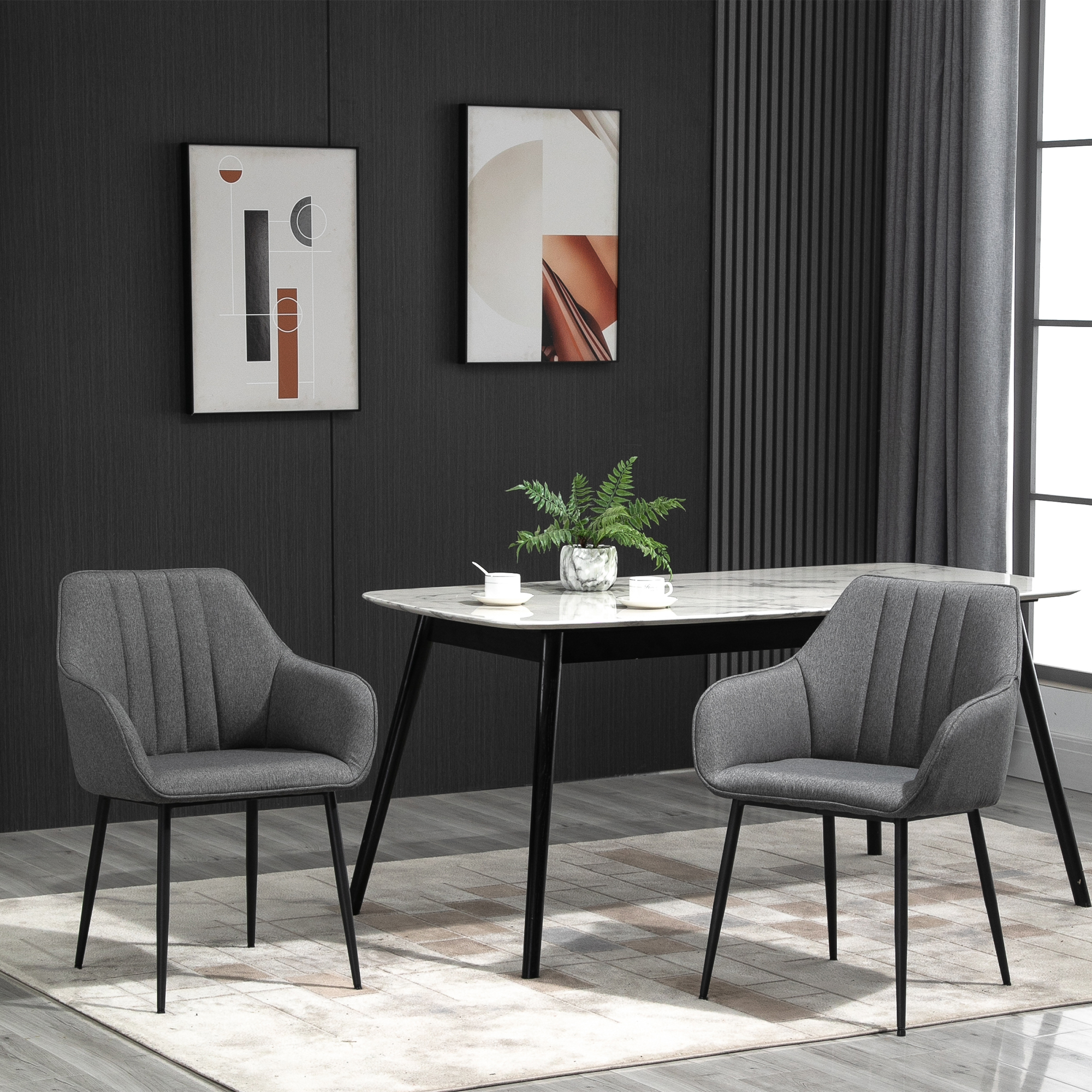 Dos sillas grises están frente a una mesa de comedor con tapa de mármol y una planta verde.