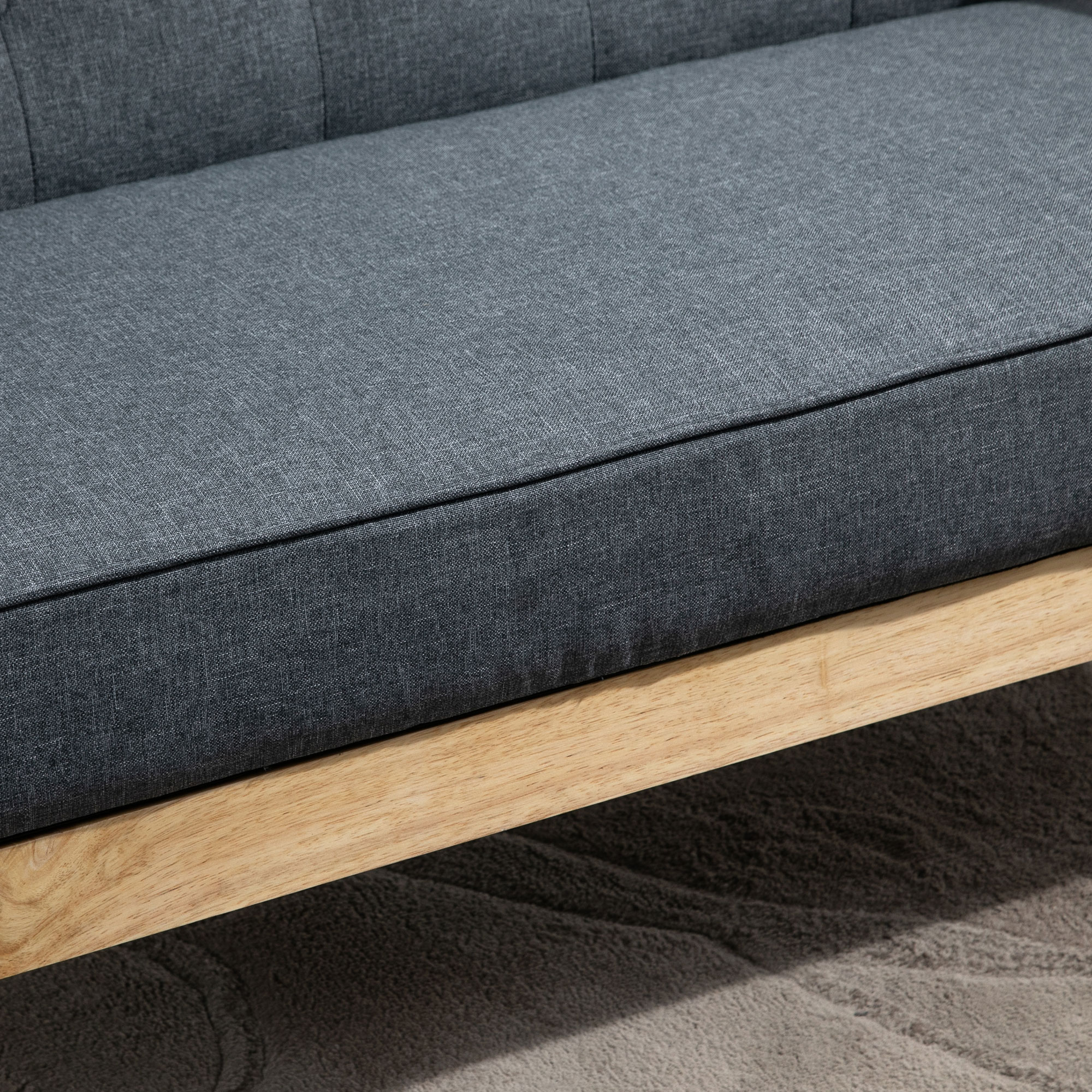 Sofá de tela gris con detalles de madera sobre una alfombra.