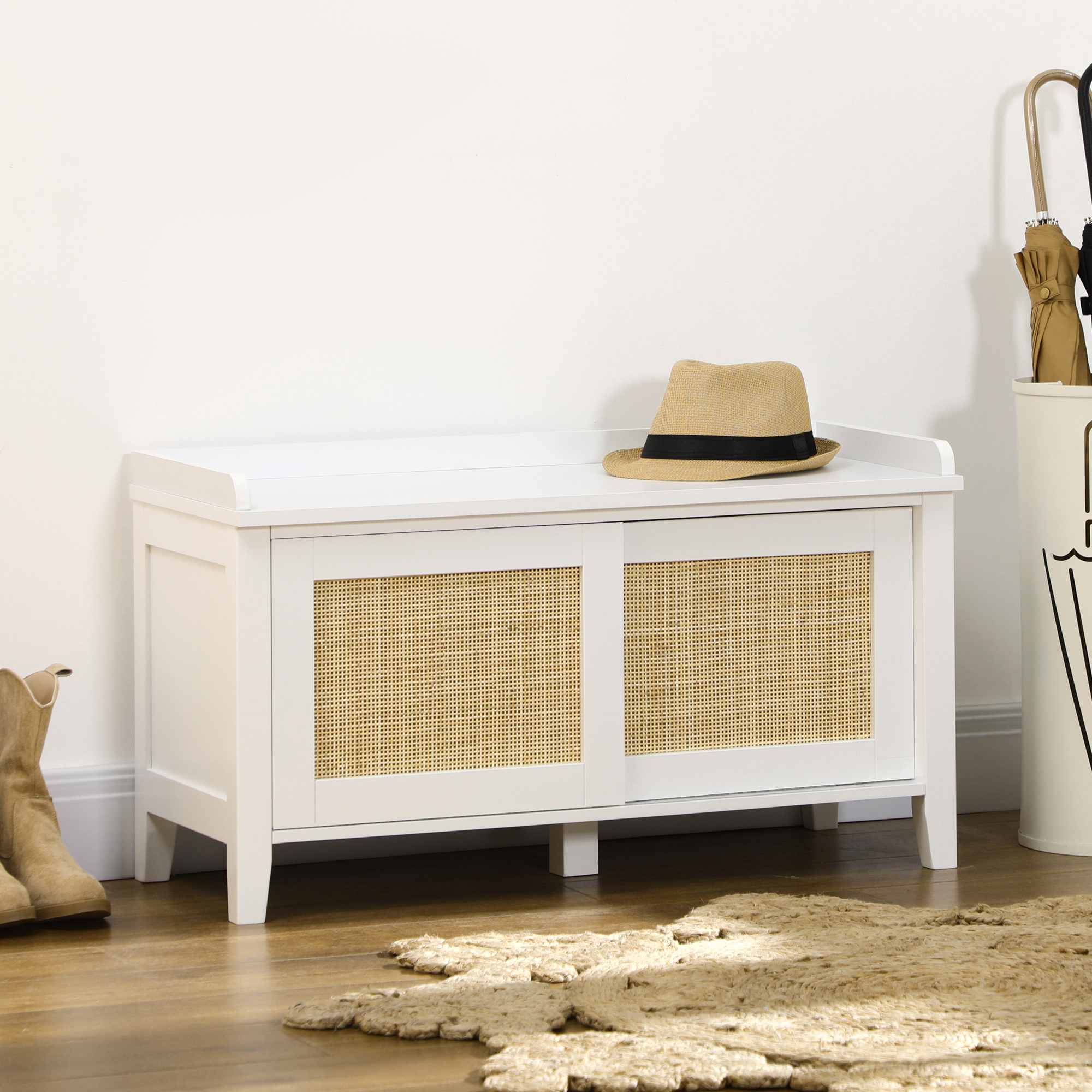 Un mueble blanco con puertas de ratán, un sombrero y botas al lado.