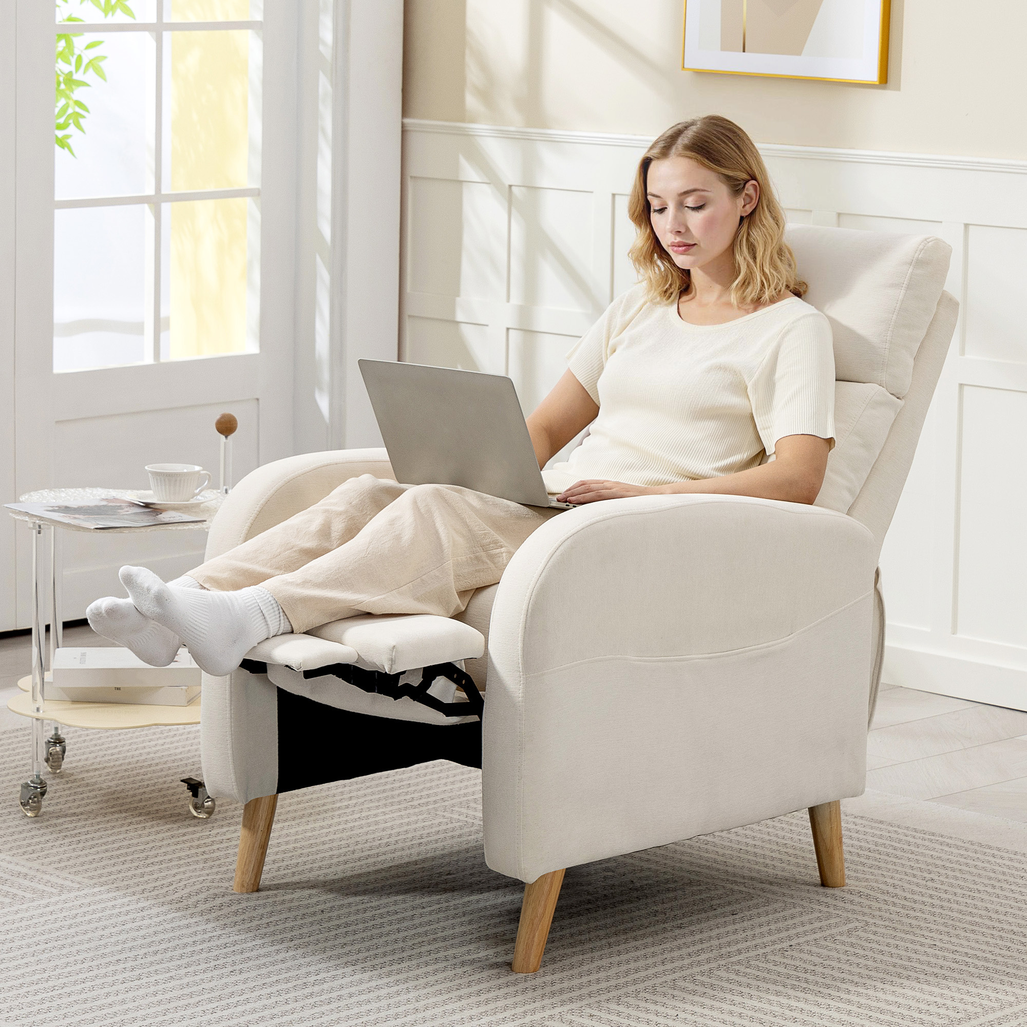 Una mujer sentada en un sillón reclinable usando un portátil, con los pies en alto.