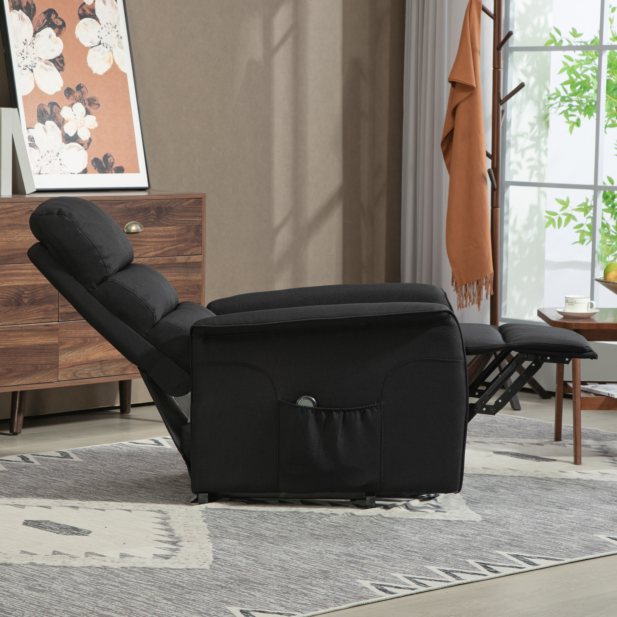 Sillón reclinable negro con reposapiés extendido, al lado de una cómoda y perchero.