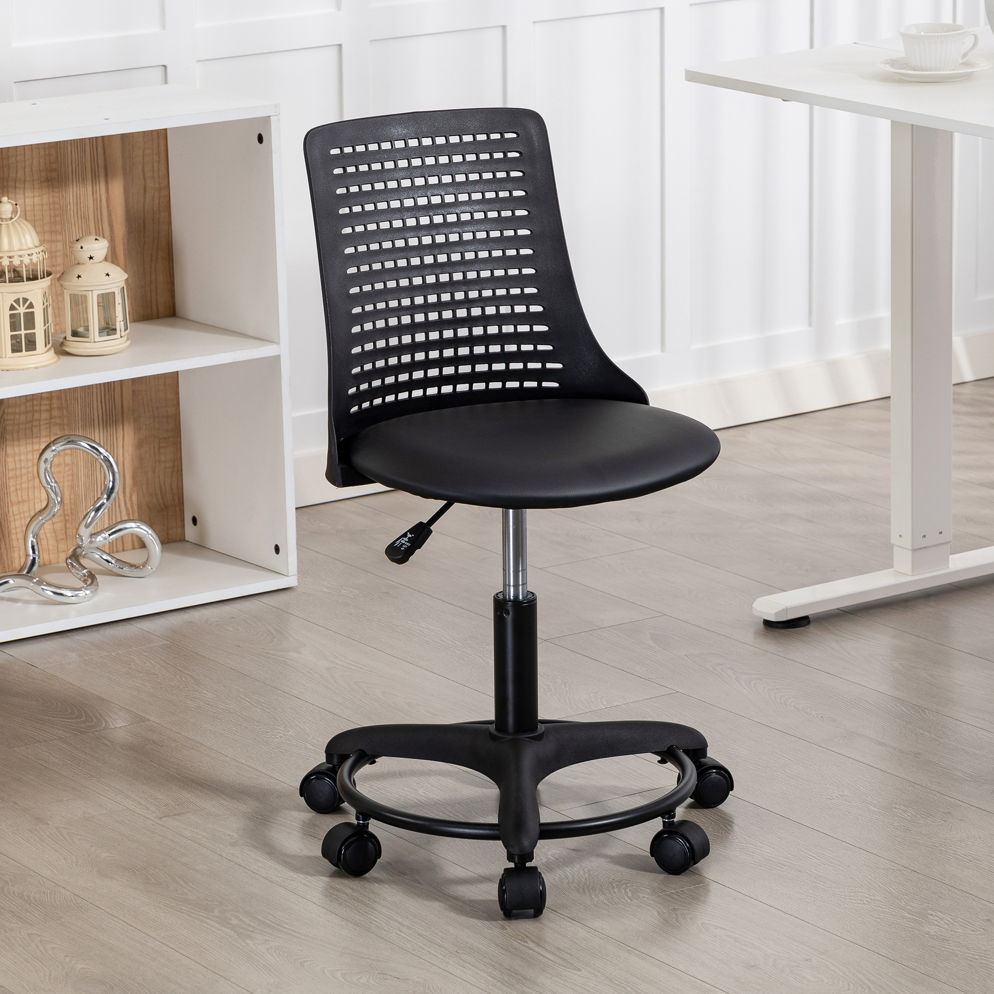 Una silla de oficina negra con respaldo de malla está sobre un suelo de madera.