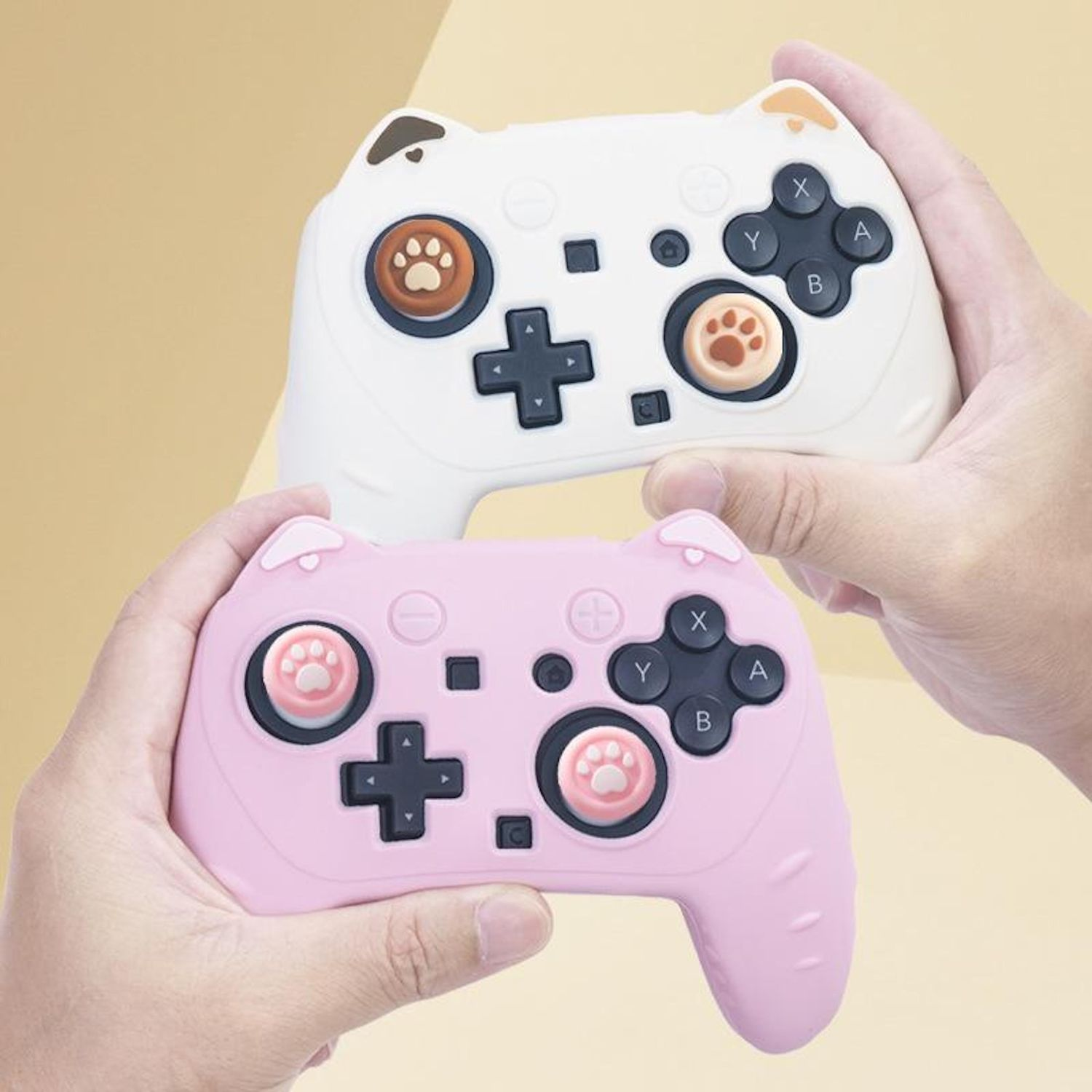 Zwei Hände halten weiße und pinke Gaming-Controller mit Katzenohren.