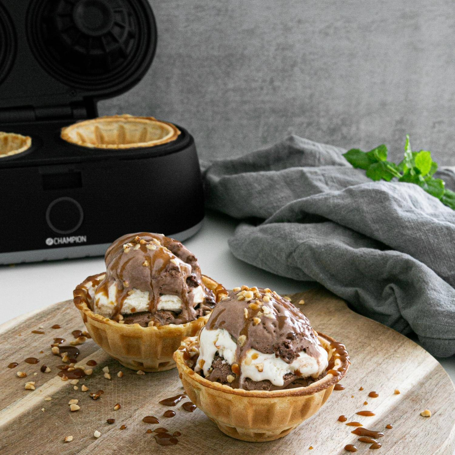 Chocolate and vanilla ice cream in waffle bowls, drizzled with nuts and caramel.