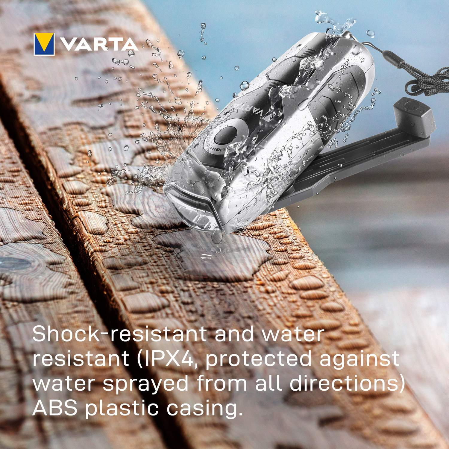Varta zaklamp besproeid met water, op houten planken.
