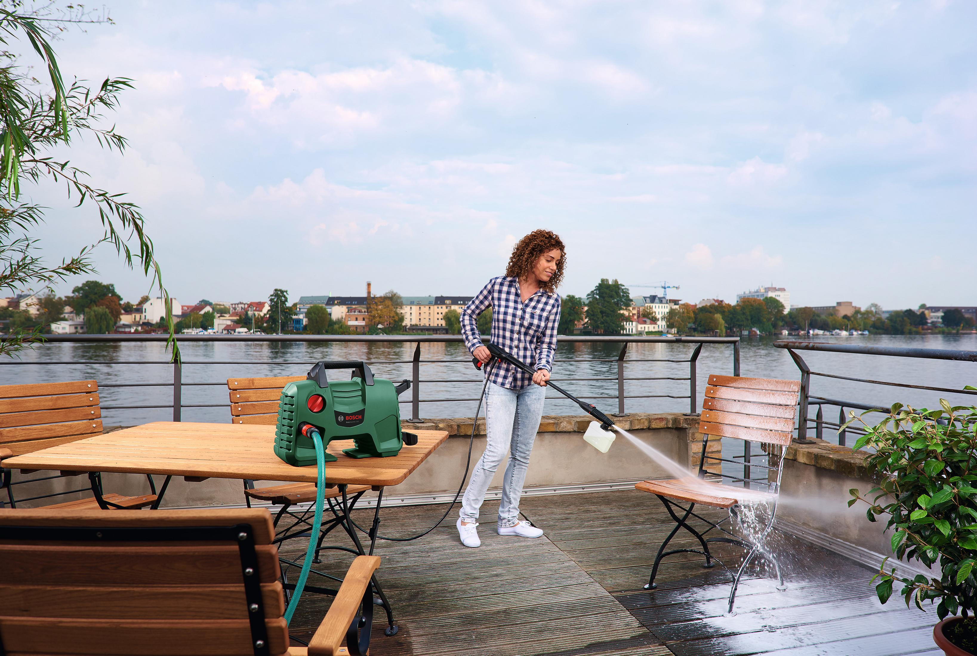 Vrouw reinigt stoel met hogedrukreiniger aan het water