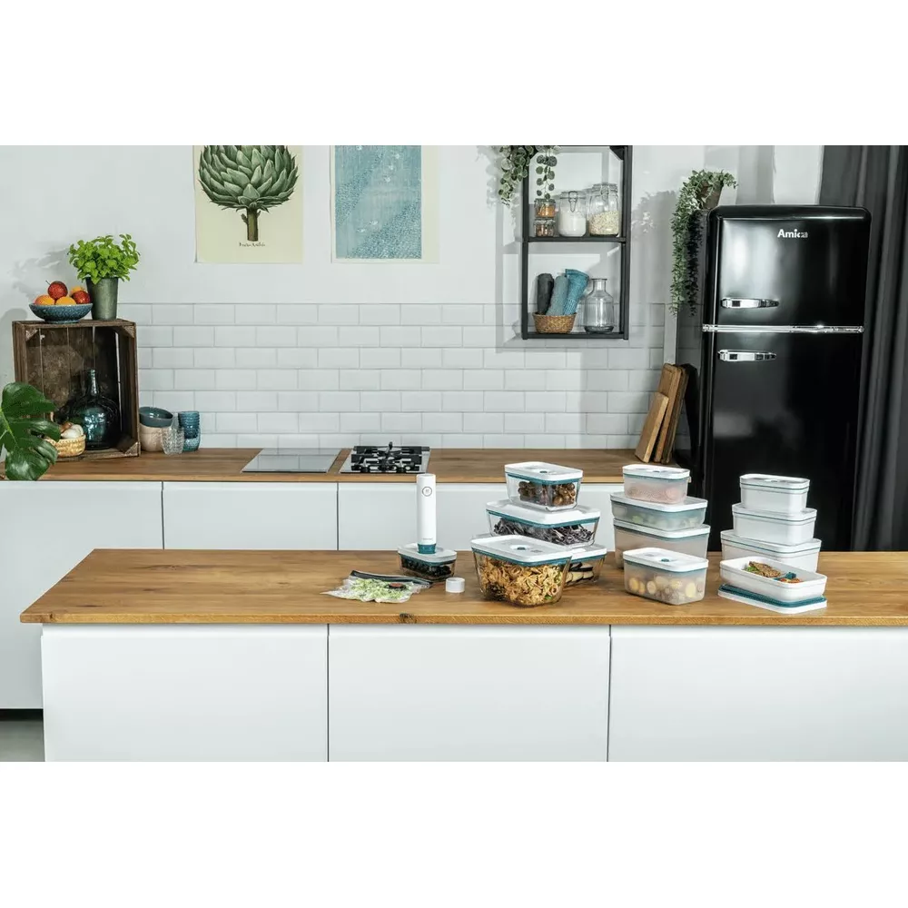 Piano di lavoro cucina con contenitori, frigorifero e piano cottura.