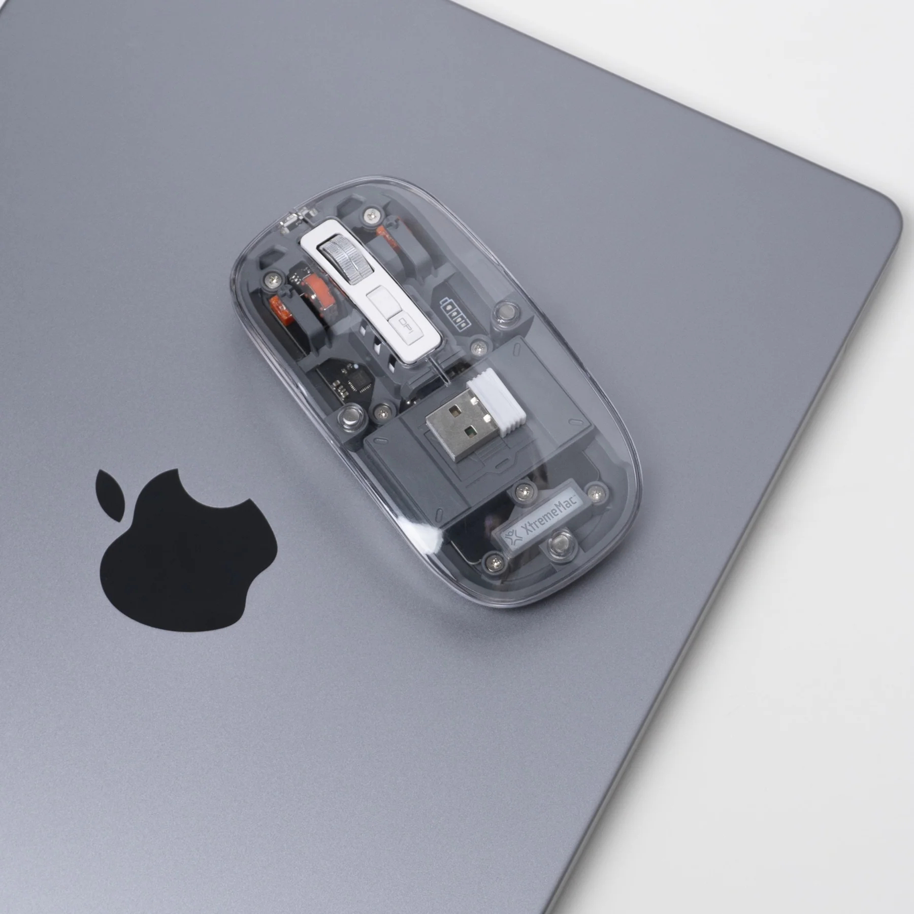 Transparent mouse on a MacBook with Apple logo. Internal components visible.