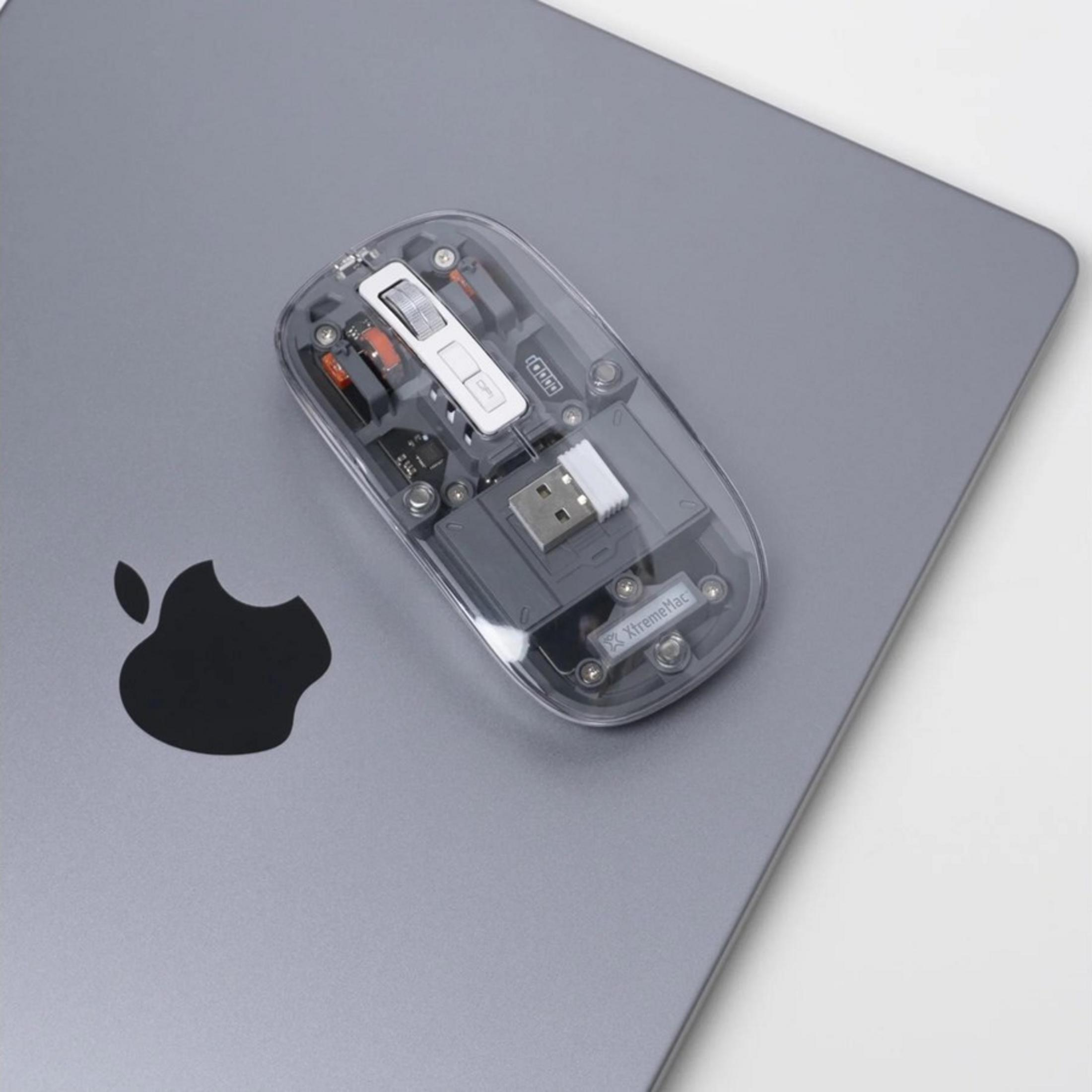 Transparent mouse with USB dongle on a MacBook with Apple logo.