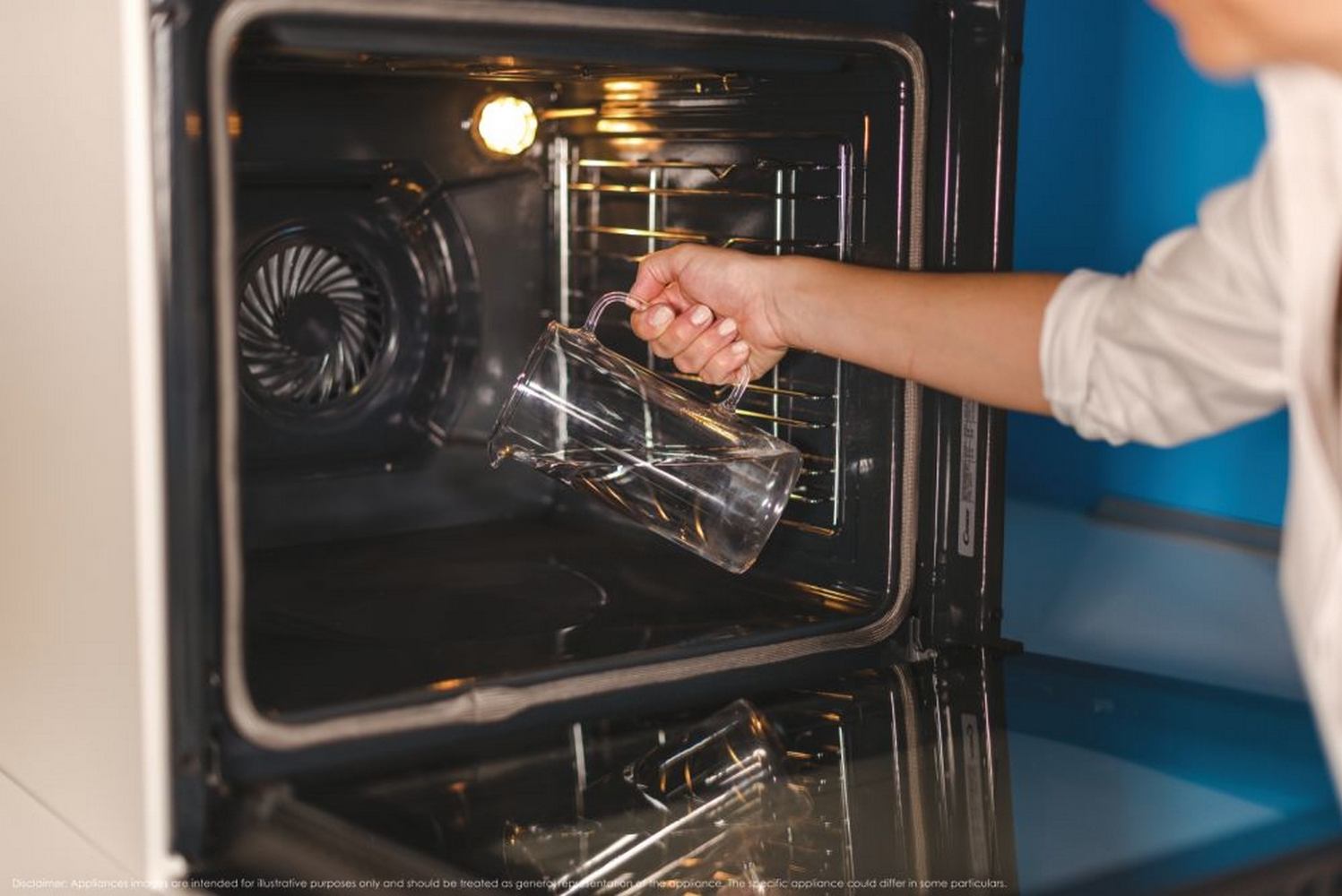 Una mano versa acqua da una caraffa di vetro in un forno.