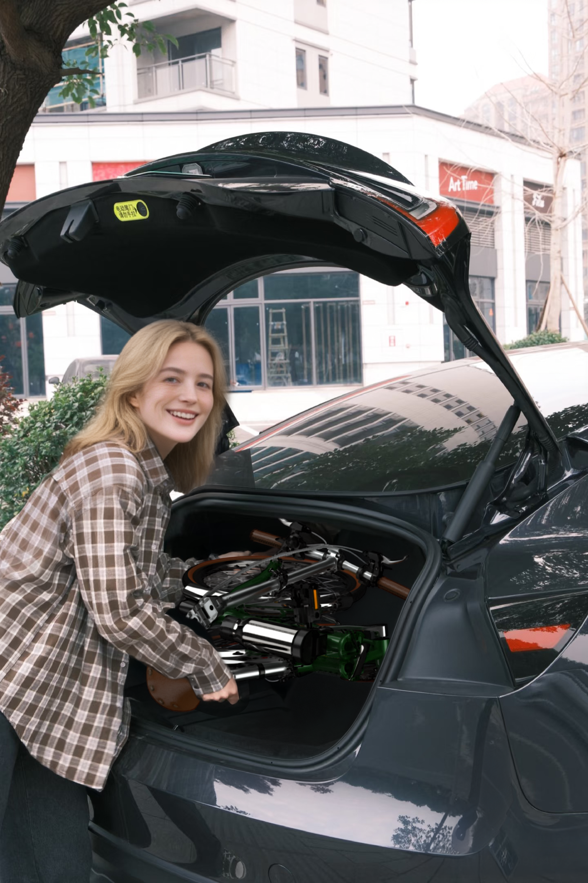 Eine junge Frau mit kariertem Hemd lädt ein Fahrrad in den Kofferraum eines Autos.