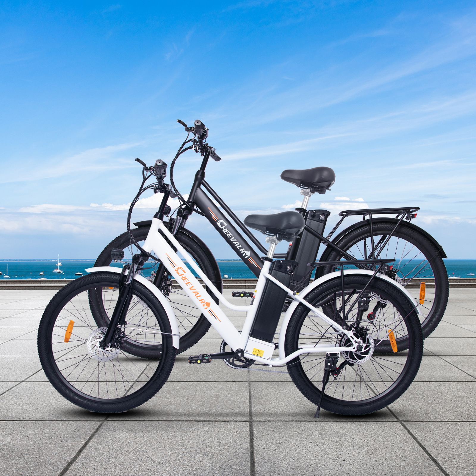 Due e-bike, bianca e nera, su un patio di pietra vicino al mare.