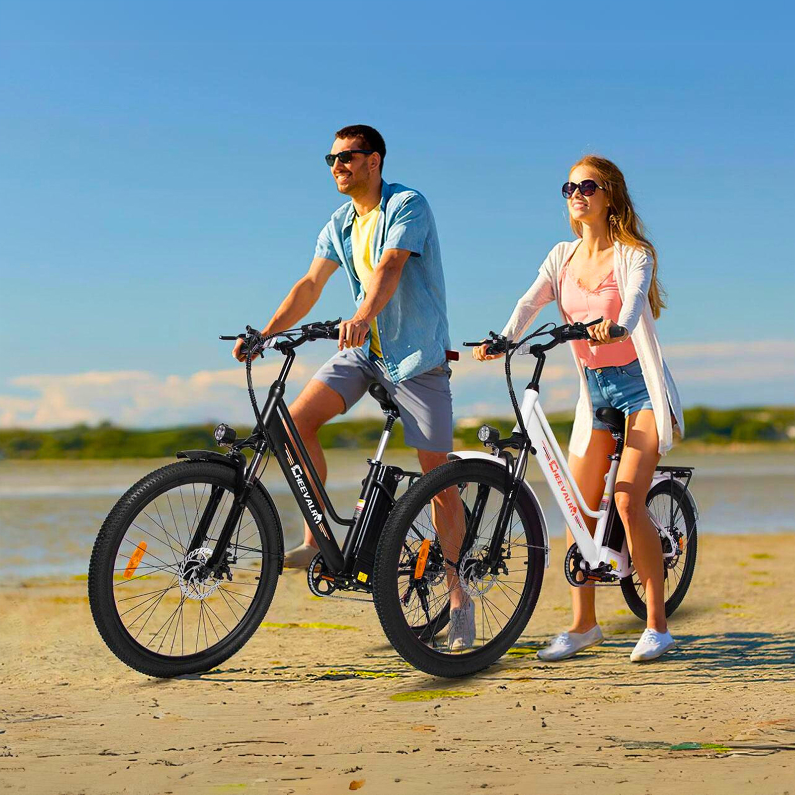 Ein Mann und eine Frau fahren Fahrräder am Strand bei blauem Himmel.