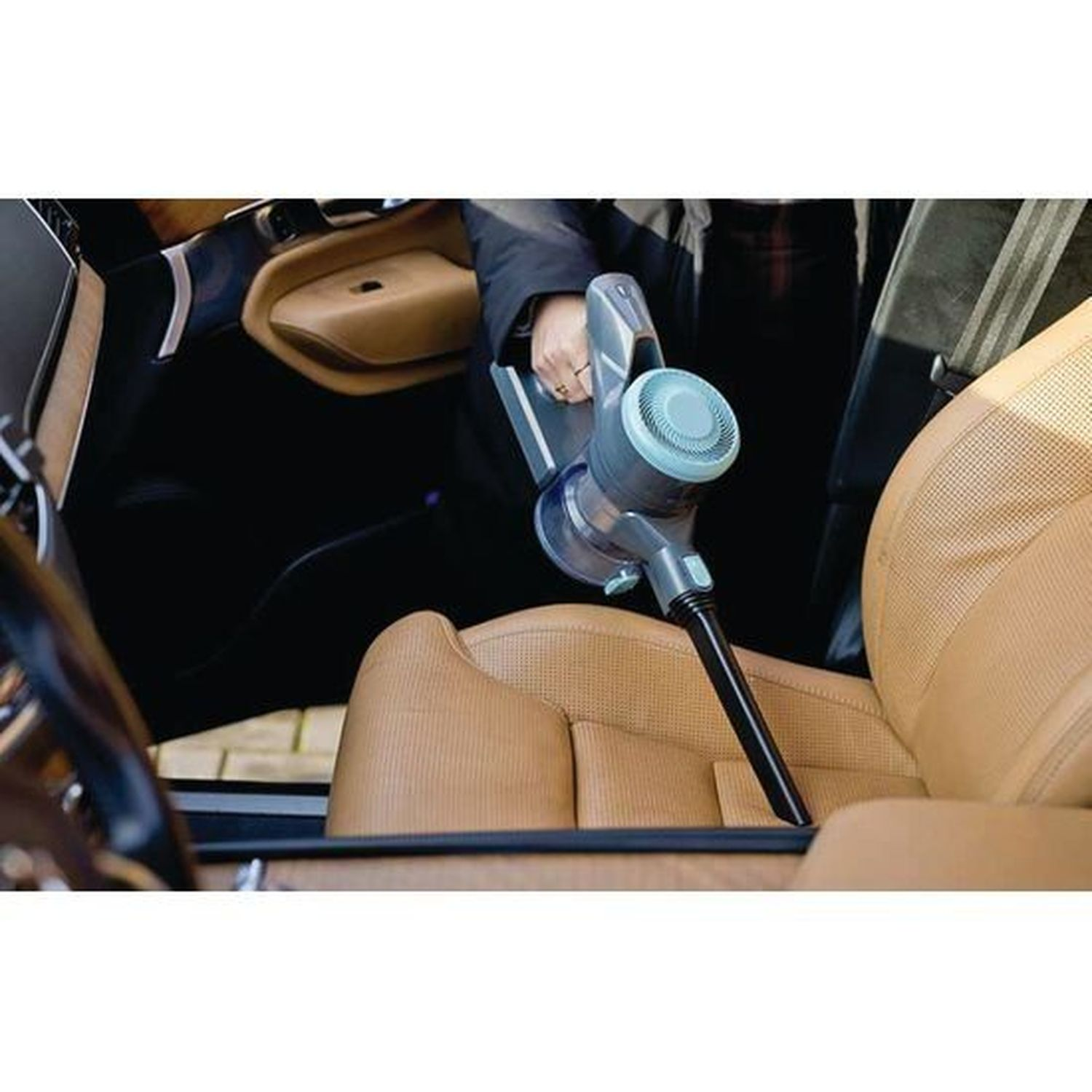 A hand vacuum cleaner is used on a car seat to clean it.