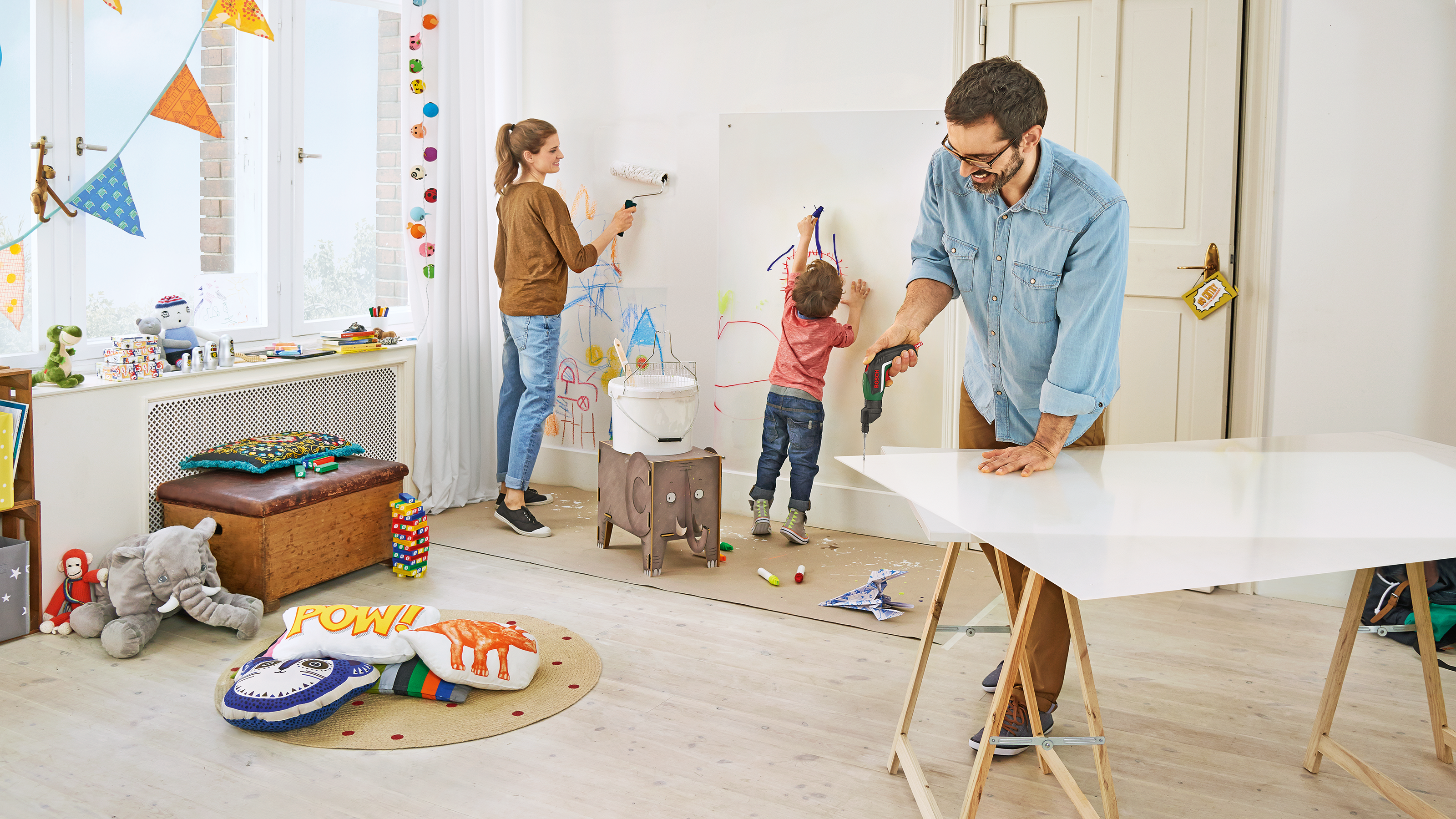 Familie malt und bohrt an einer Whiteboard in einem Raum mit Spielzeug.