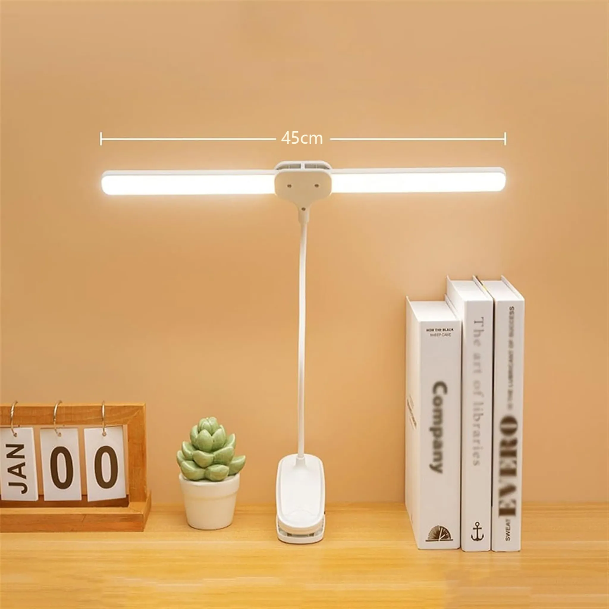 Ein weißes Clip-On-Licht über einem Kalender, einer Pflanze und Büchern.