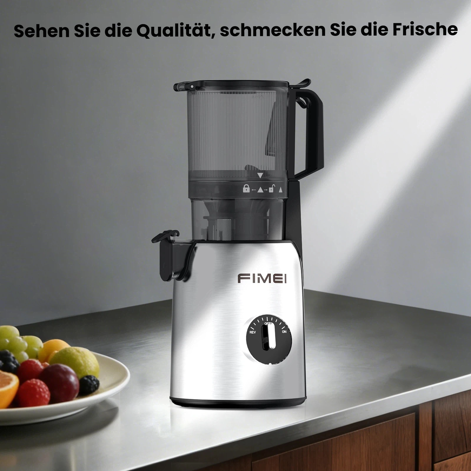 Ein silberner Entsafter steht auf einer Arbeitsplatte neben einer Schale mit Obst.