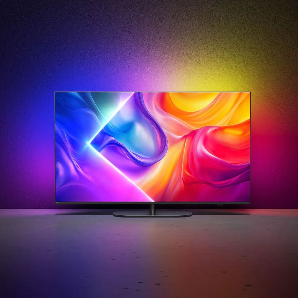 Modern bir TV, renkli ışıklarla aydınlatılmış karanlık bir zeminde duruyor.