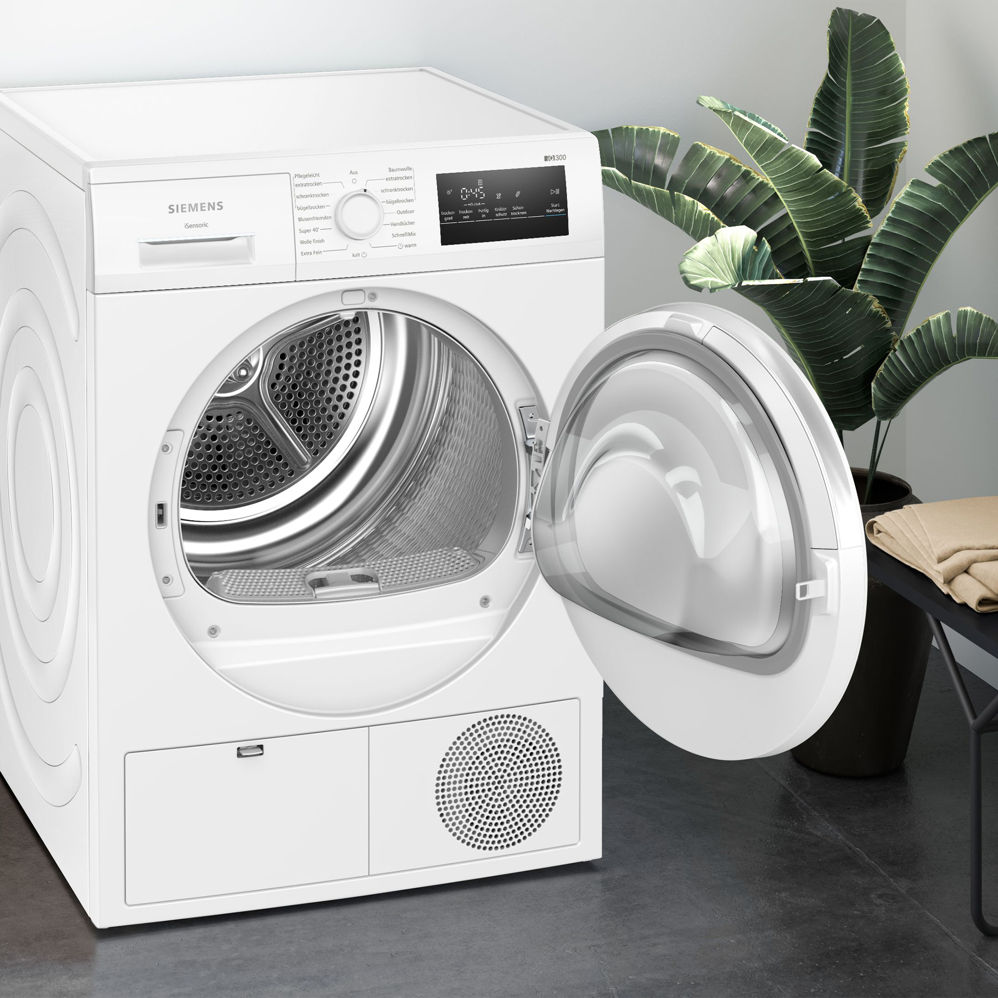 Weiße Siemens Wäschetrockner mit geöffneter Tür, innen glänzende Trommel. Neben einer Pflanze.