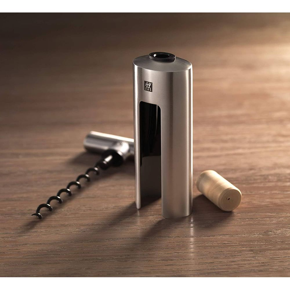 Un cavatappi argentato con manico nero e un tappo di legno su legno.