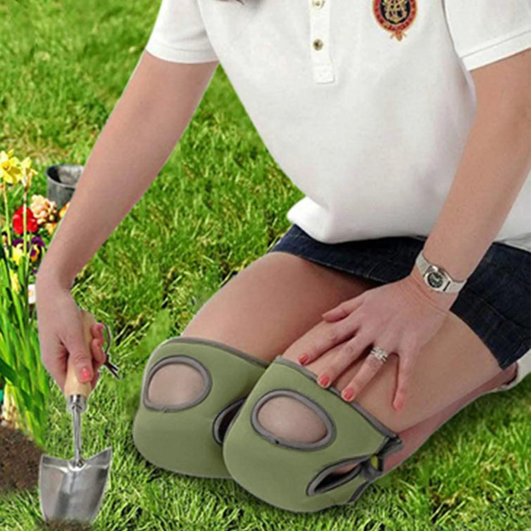 Person kniet im Gras und pflanzt Blumen mit einer Schaufel.