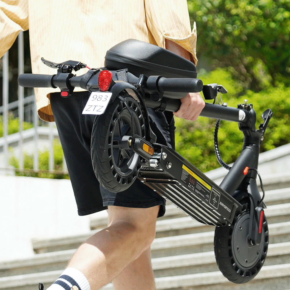 Mężczyzna niesie czarną hulajnogę elektryczną z torbą, schodami i drzewami w tle.