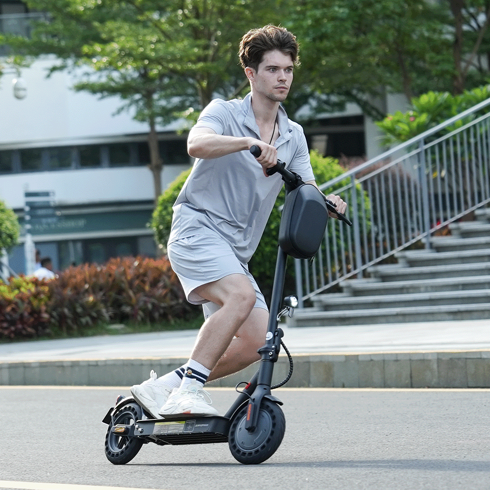 Mężczyzna jedzie czarną hulajnogą elektryczną po asfaltowej drodze.