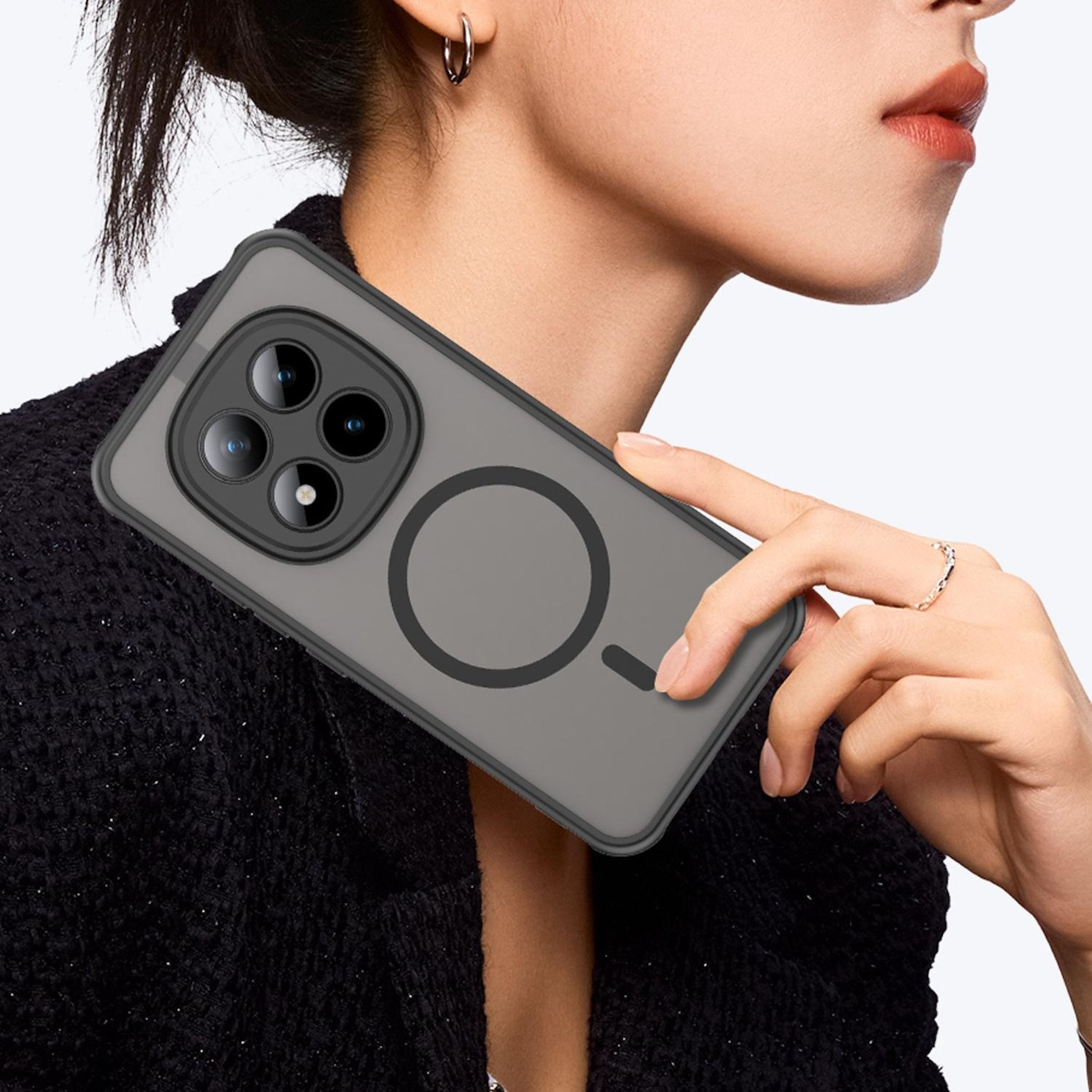 Eine Person hält ein graues Handy mit drei Kameras und magnetischem Ring.