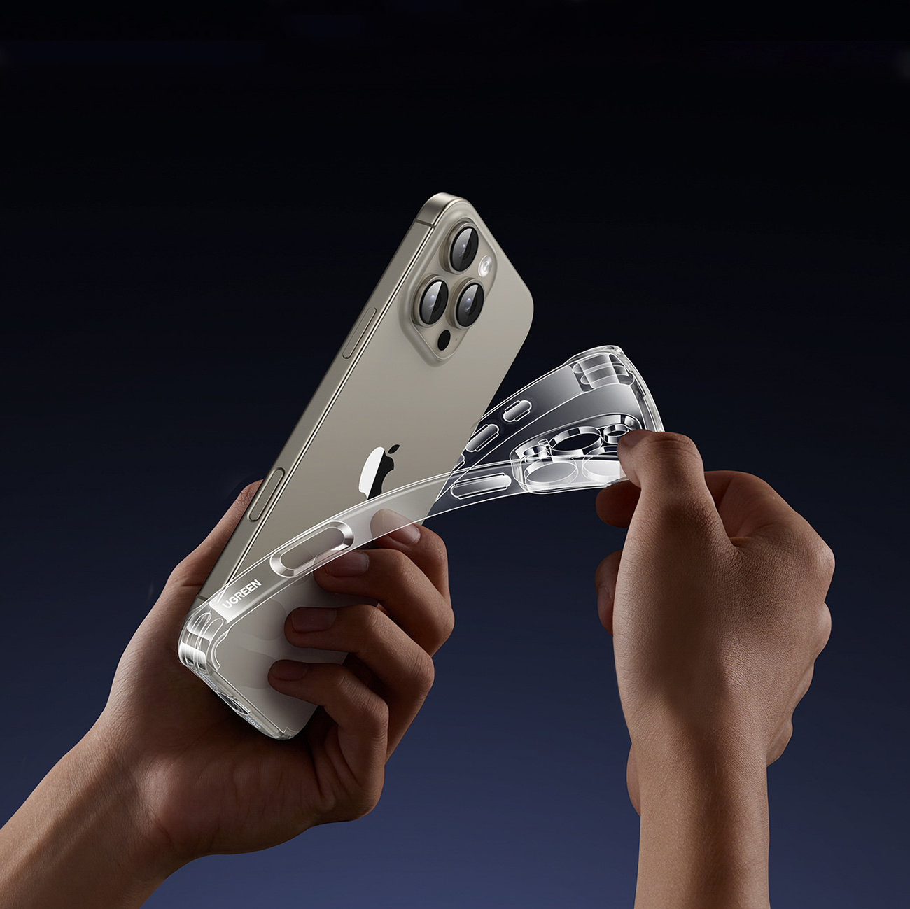 Dłonie zakładające przezroczyste etui na srebrny iPhone na ciemnym tle.