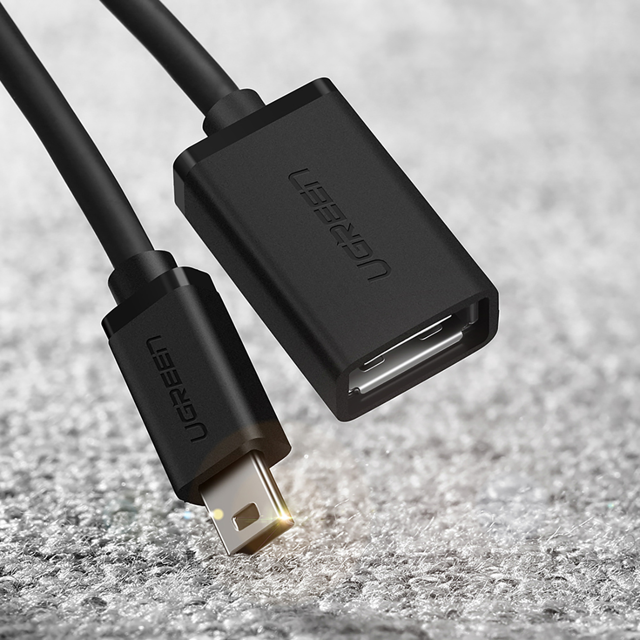 Czarny kabel USB z wtyczką mini USB i żeńskim portem USB-A na szarym tle.