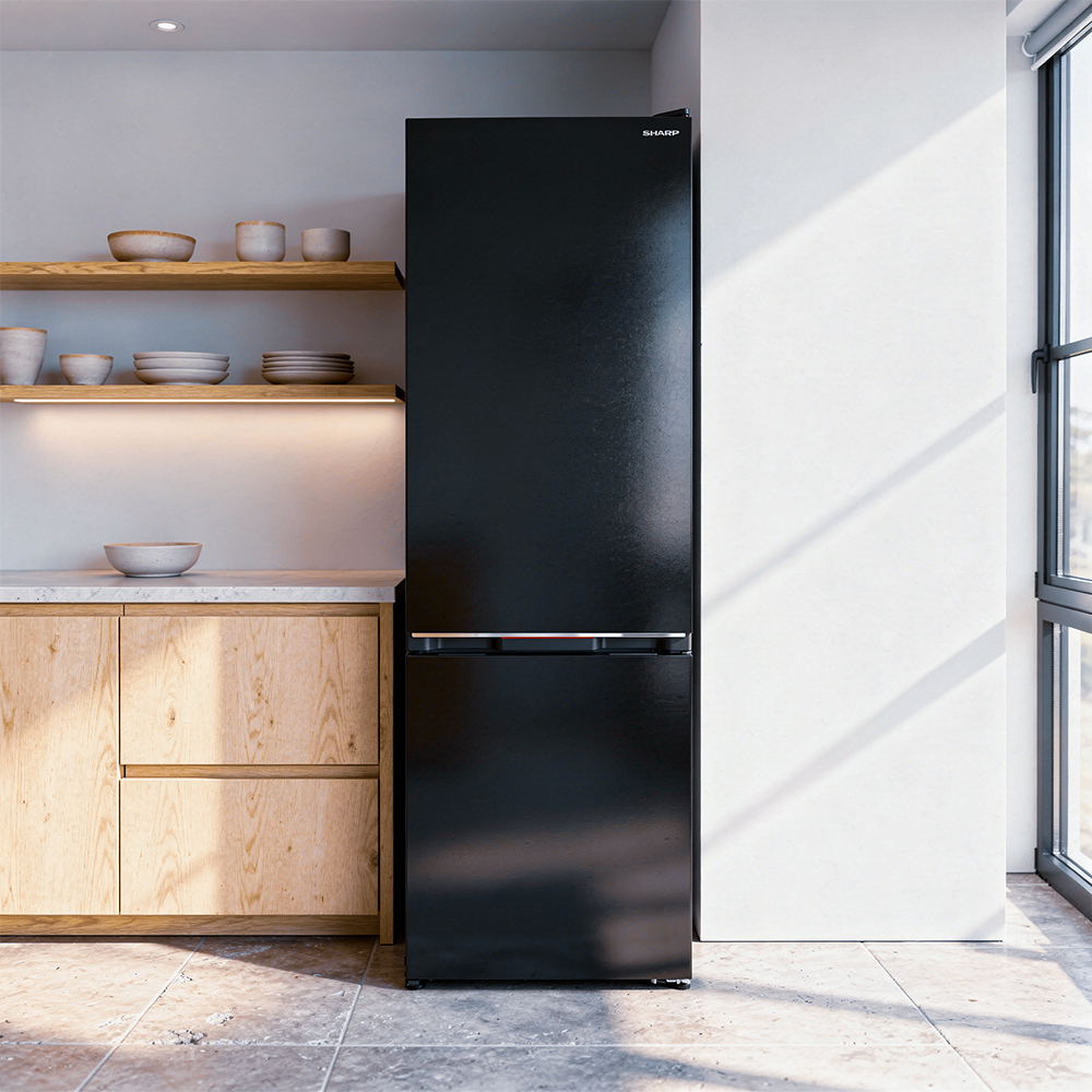 Black refrigerator next to wooden cabinets and shelves with dishes.