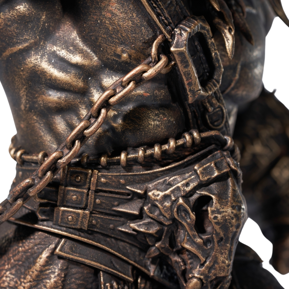 Bronzefigur mit Muskeln, Ketten und Rüstung. Detailaufnahme des Oberkörpers.