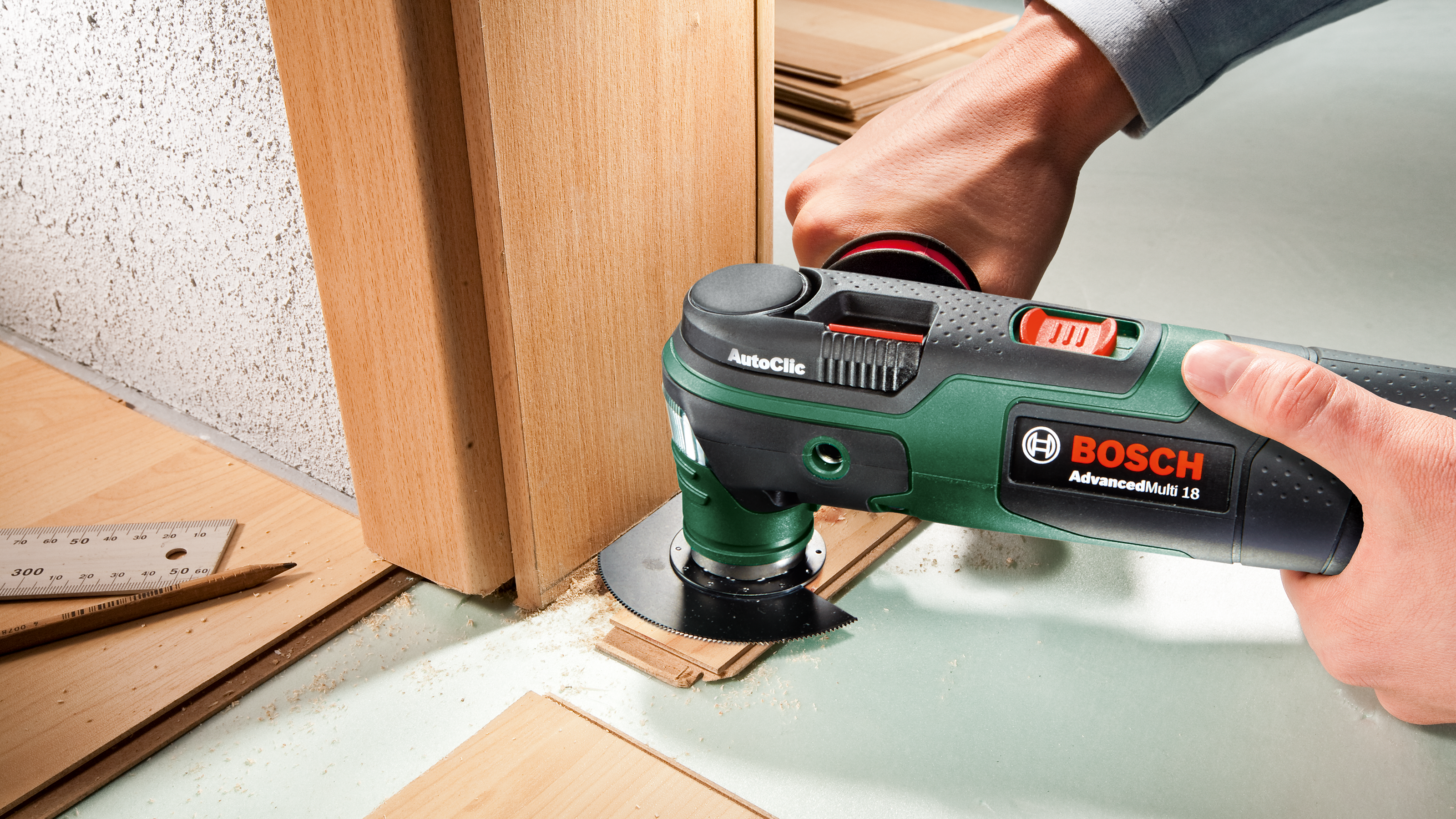 Werkzeug schneidet Holz; daneben liegen Holzbretter, ein Lineal und ein Bleistift.