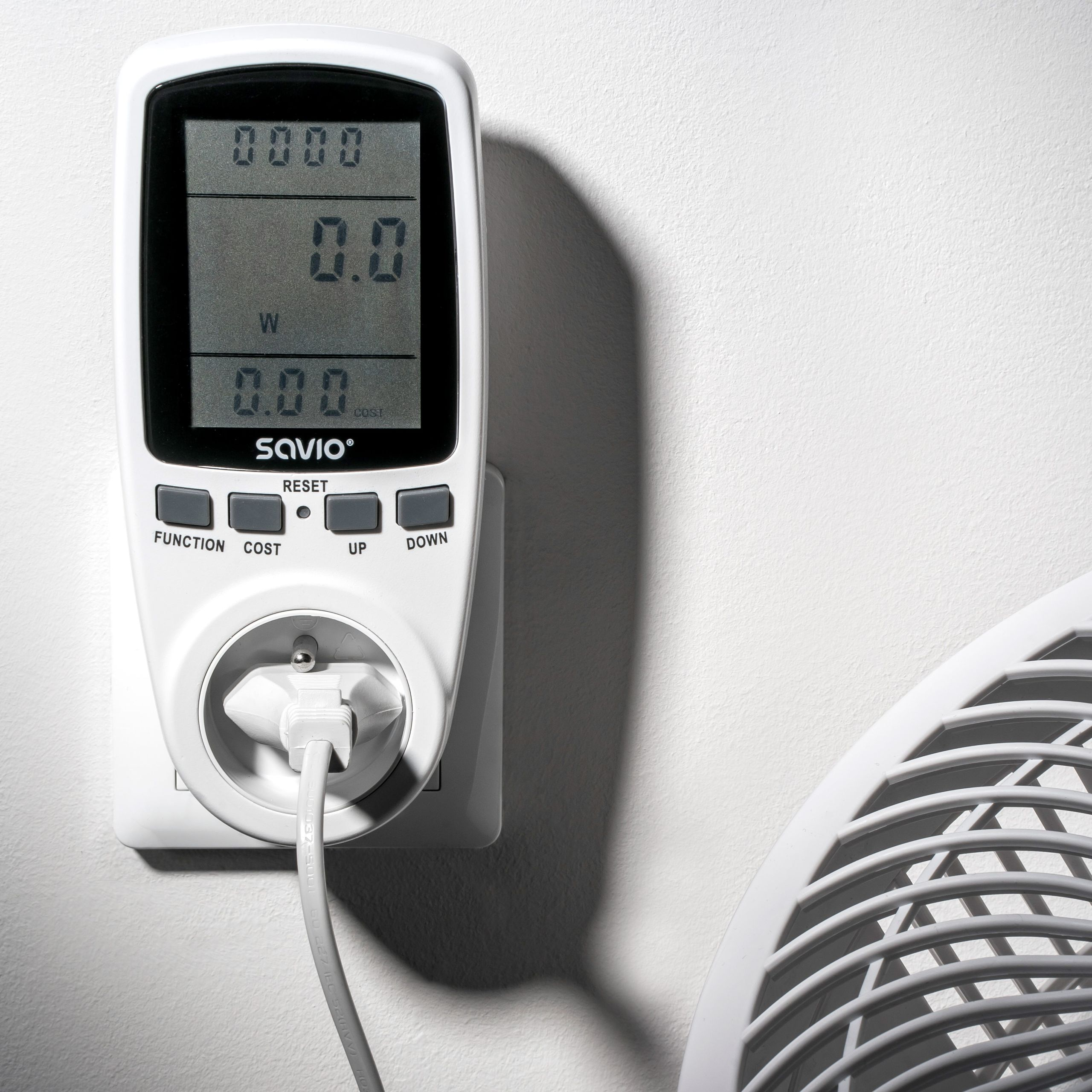 Biały miernik energii z cyfrowym wyświetlaczem jest podłączony do gniazdka.