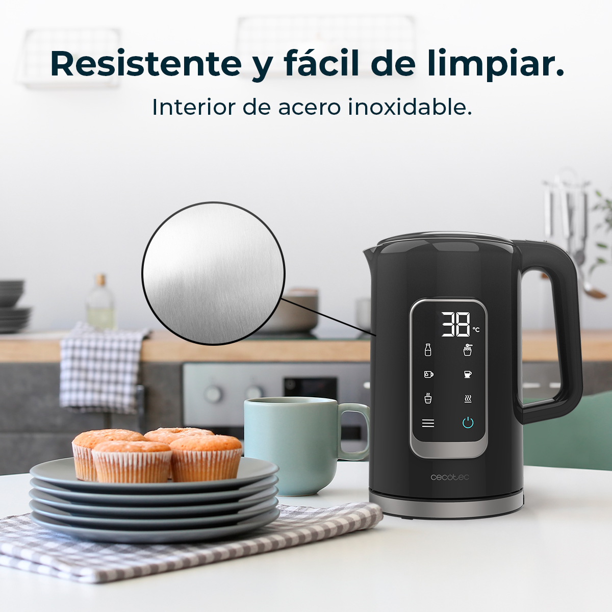 Un bollitore elettrico nero con display digitale è su un tavolo, con muffin e una tazza nelle vicinanze.