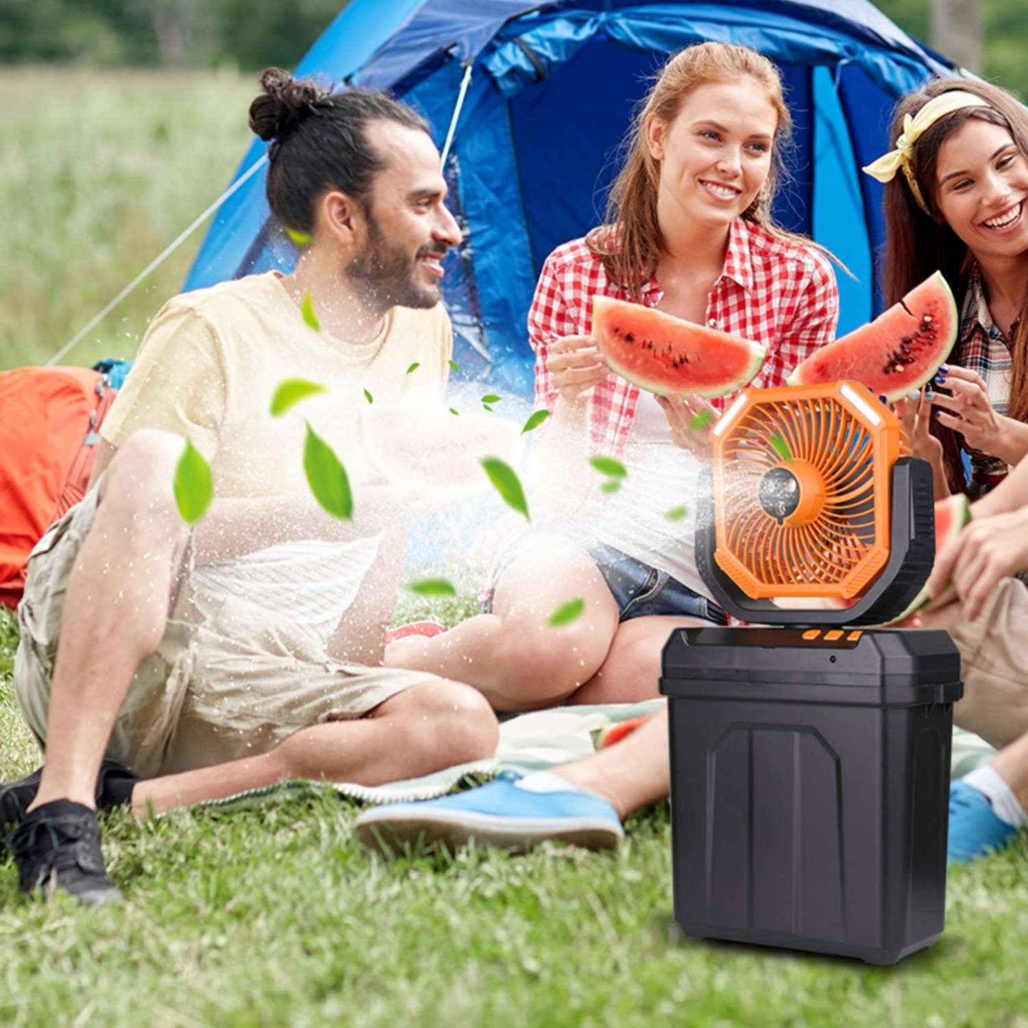 Freunde campen mit Wassermelone und tragbarem Lüfter vor einem blauen Zelt.