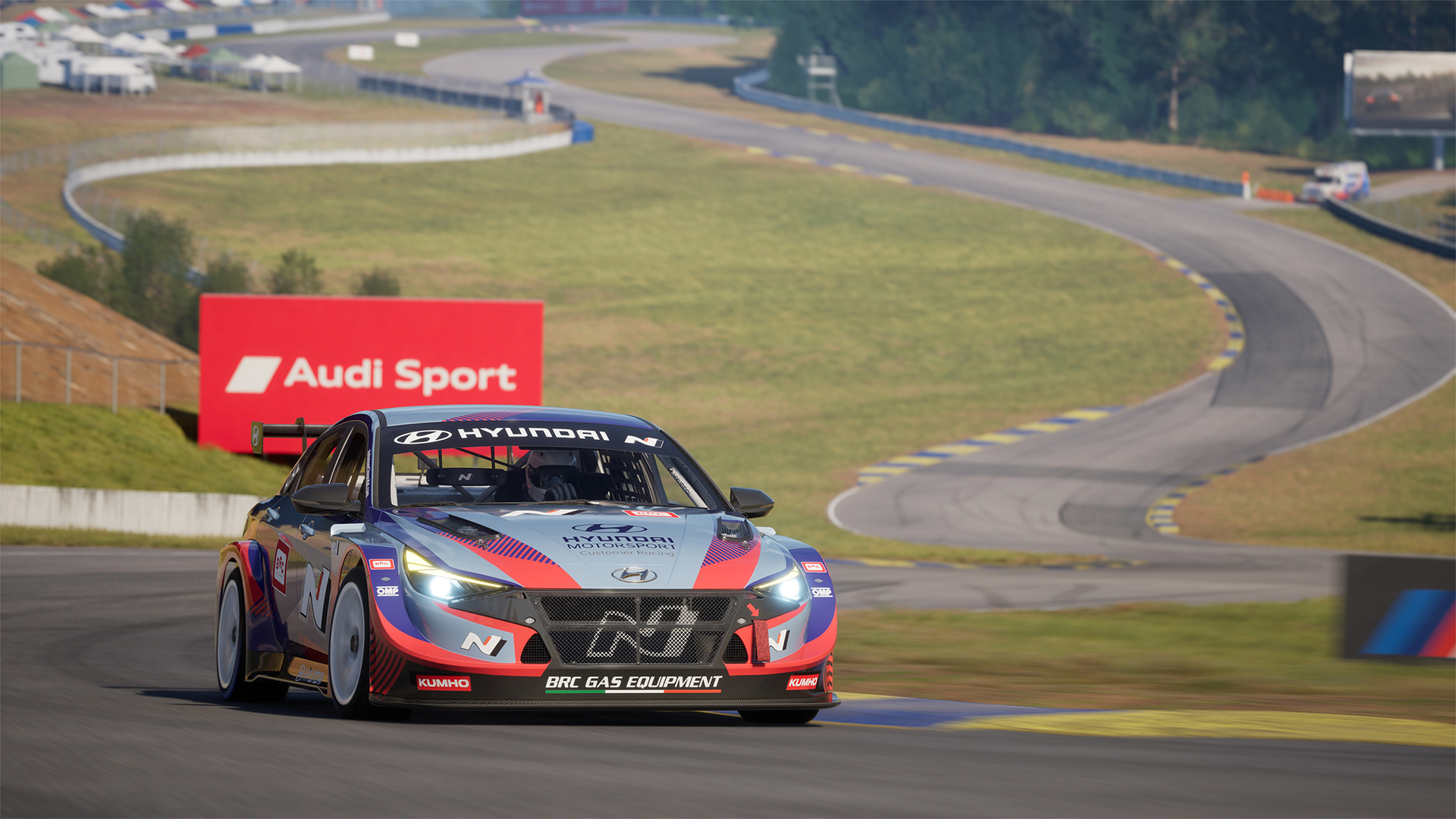 Un'auto da corsa Hyundai blu e rossa corre su una pista con un cartellone Audi Sport sullo sfondo.