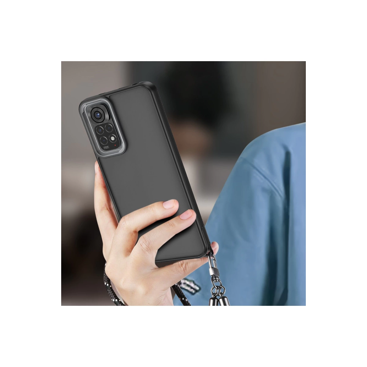 Bir el, dört kameralı ve bilek kayışlı siyah bir akıllı telefon tutuyor.
