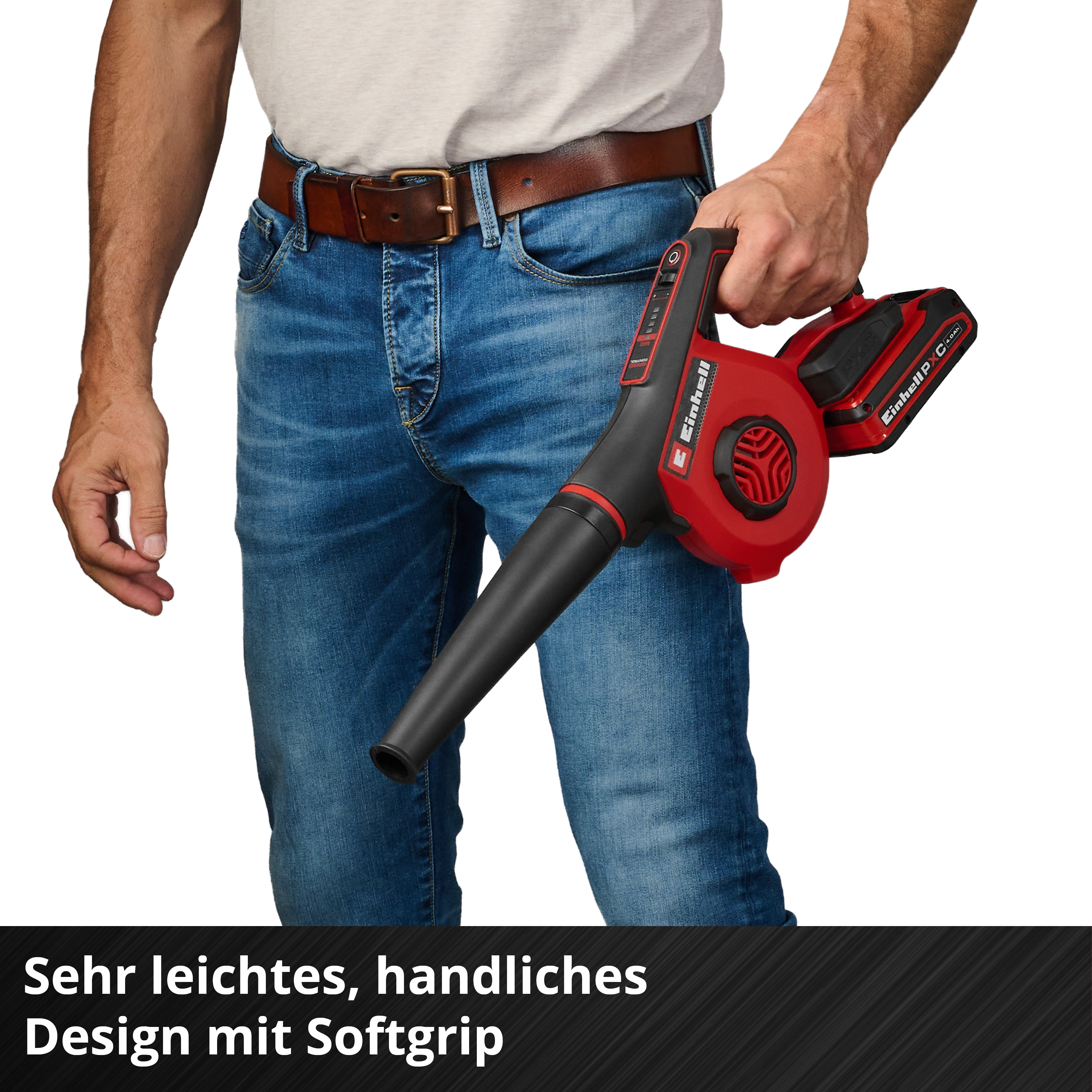 Mann hält roten Laubbläser mit Akku, trägt Jeans und braunen Gürtel.