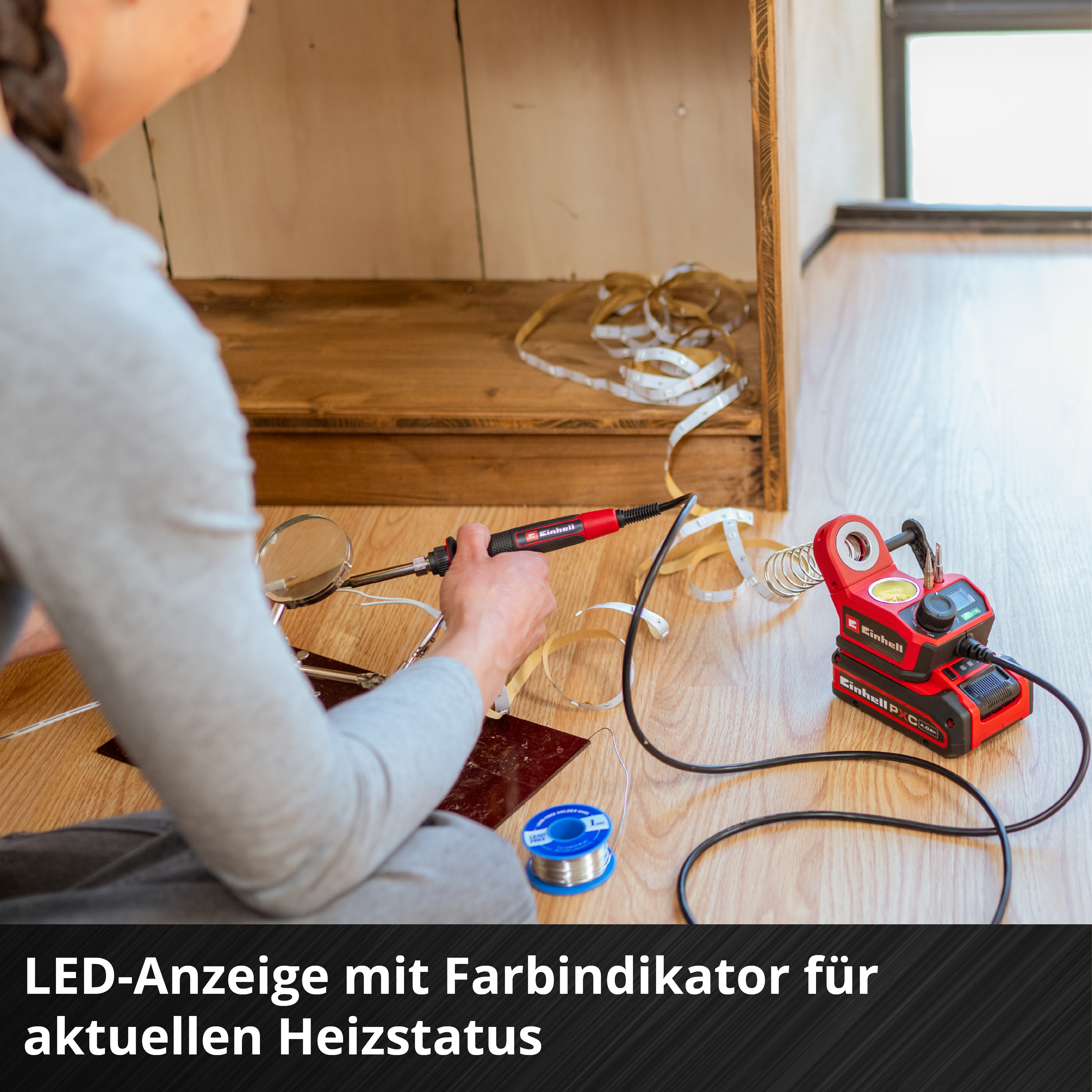 Person lötet an LED-Streifen mit einem roten Einhell-Lötkolben und Batteriegerät.