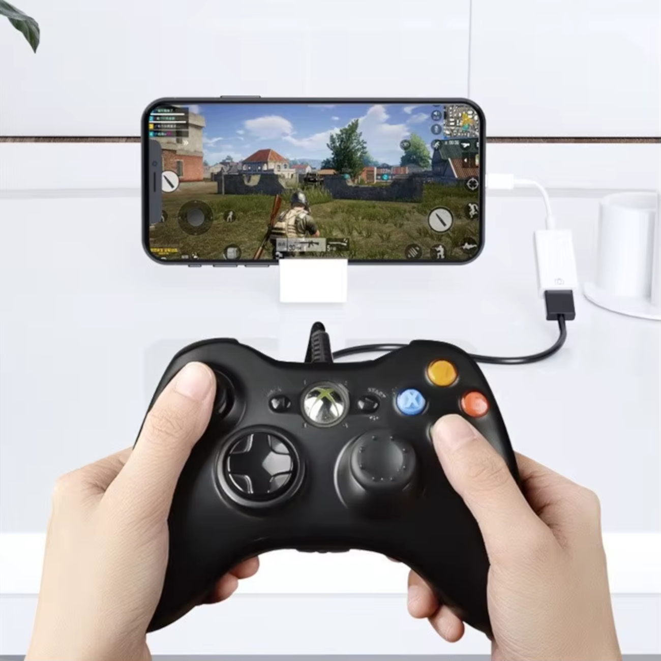 Eine Hand hält einen schwarzen Controller, der mit einem Smartphone verbunden ist, auf dem ein Spiel läuft.