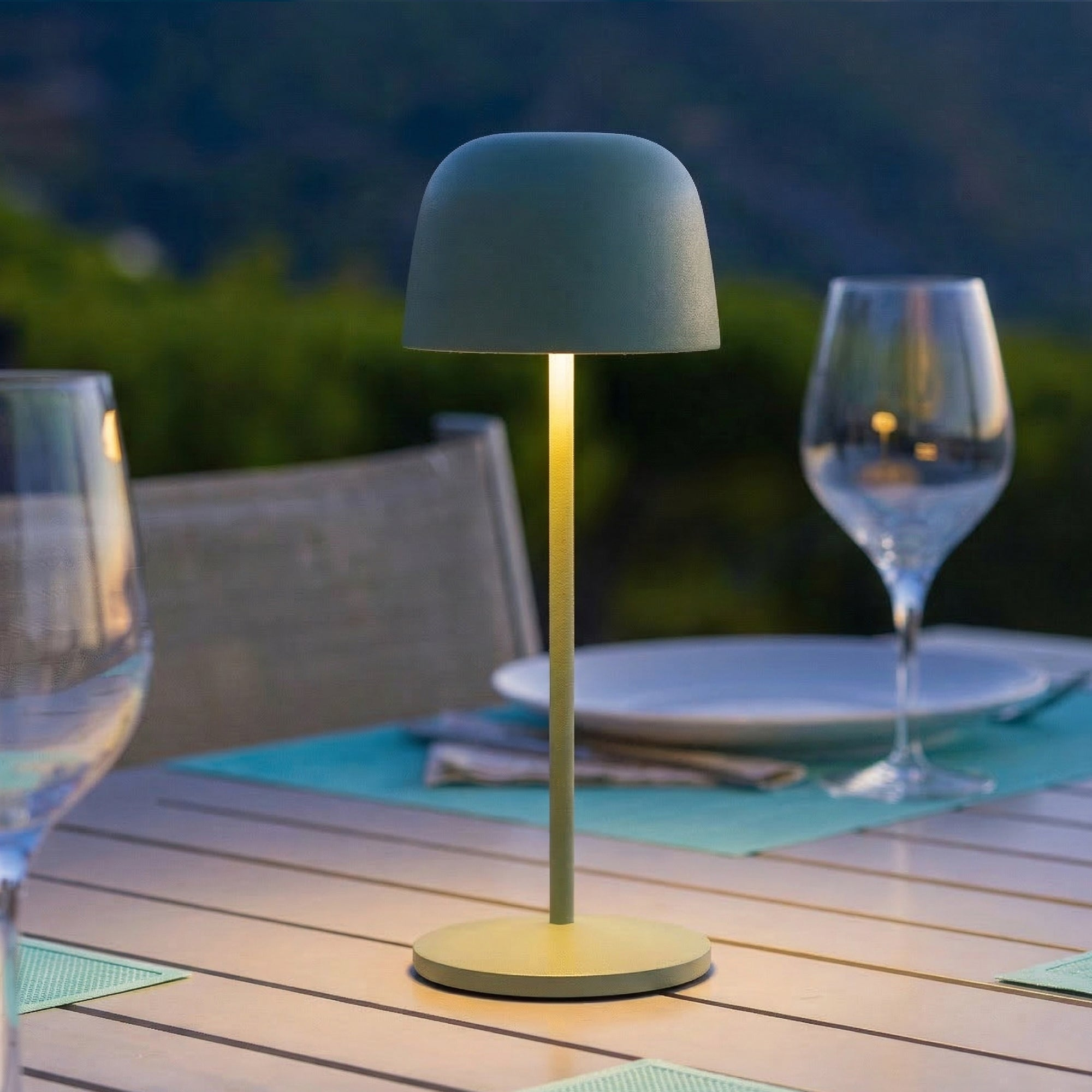 Eine grüne Lampe steht auf einem Tisch mit Gläsern und Tellern.